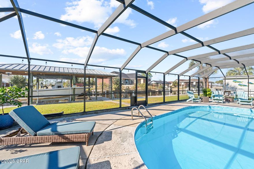 Welcome to an extraordinary outdoor entertainer's paradise set along 120 feet of waterfront canal, complete with a 2020 custom-built dock, boathouse, and remote-controlled aluminum boatlift engineered with a custom boat-wash system featuring surrounding spray nozzles and a flush valve to clear saltwater from the motor. The dock offers water, electrical outlets, security lighting, a starboard-and-aluminum fish cleaning station, floating jet ski pads that rise and fall with the pilings, and a custom bird-deterrent system. The boat, jet skis, and pads are negotiable. A brand-new 2019 seawall with French drains ensures proper drainage, keeping the yard pristine.

Starting with the showpiece of the home, the resort-style 50x60 screened pool enclosure—recently updated with new screens—is an oasis designed for true indoor-outdoor living. A large inground chlorine pool is surrounded by an expansive deck perfect for lounging and entertaining. Evening ambiance shines with string lighting, a firepit, and dedicated seating and dining zones, complemented by an outdoor TV, Hot Springs Swim Spa, outdoor shower, removable child safety screen, and even a dartboard with its own spotlight. Three ceiling fans keep the area cool, and three convenient exits lead to the grassed and gated backyard, each equipped with doggy doors for pets.

The custom outdoor kitchen is the heart of the outdoor living experience, constructed with materials that will not rust or deteriorate. A 10-foot concrete-topped bar anchors the space, accompanied by a double kegerator, 2-drawer refrigerator, pellet-ice maker, sealed storage cabinets, bottle opener with trash drawer, and sealed paper towel drawers. The large sink includes a spray faucet, instant hot water, and garbage disposal. A sliding glass window from the interior kitchen opens to the bar for easy serving. Pendant lighting, separate task lighting, built-in countertop outlets, and a dedicated sub-panel with individual breakers make this an entertainer's dream. The Memphis Elite WiFi-enabled pellet grill/smoker allows temperature control from your phone—perfect for smoking dinner while out boating at Shell Island.

Inside, the home continues to impress with an updated kitchen featuring a built-in coffee/wine bar, two pantries with sliding drawers, double oven, and beautiful ceramic tile throughout. The dining room is currently a playroom but easily converts back. A spacious, welcoming front porch offers motion lighting and coded entry, leading into a large foyer with coat closet and a living room with a real wood-burning fireplace, custom shelving, Bose wireless surround sound, and large windows overlooking the pool and waterfront.

The 20×10 primary bedroom includes private pool access, a double-vanity en suite bathroom, and a walk-in closet with custom built-ins. Guest bedrooms are located separately from the primary and offer generous closet space for storage.

The 24x28 detached garage and workshop are exceptionally engineered with pass-through garage doors allowing a boat trailer to access an additional boat pad. A dedicated lawn mower garage features its own door and chain hoist platform raises a gas caddy to easily fill lawnmower and gas can. The workshop includes a workbench with shelving, a 50-amp RV plug, and a fully engineered attic with a 8x6 wide attic, 6' walkway with 3' of storage on each side, a hoist-pulley system for lifting items without a ladder although a ladder is available as well. A separate pool-equipment room sits conveniently next to the pool area.

Additional upgrades include: 2019 HVAC systems, 2019 windows, 2019 seawall, 2020 boatlift/boathouse, a 4-zone irrigation system with separate well and 1-microparticle Eco filtration, motion-sensor lighting at the dock/workshop, and a full home security system.

This home is a true waterfront destination—crafted for luxurious entertaining, seamless indoor-outdoor living, and unforgettable days on the canal