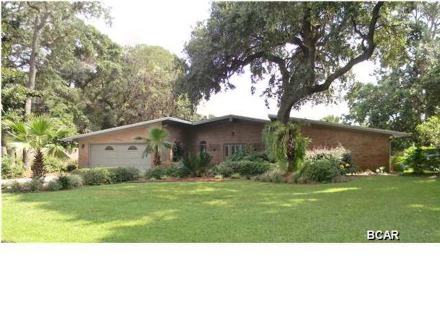 OWNER MOTIVATED - BRING OFFERS!! GRAND LAGOON WATERFRONT HOME w/Gulf & Bay Access by Boat! 105 feet on the water located on private & quiet street tucked away just off of North Lagoon Drive - 1/2 acre lot. 10 minutes to the Gulf of Mexico by boat and 5 minutes to the beach by car!! Huge outdoor living space w/ Screened Lanai & Heated Pool. Covered Boat Dock w/10,000lb Lift, water & power - deep water channel in this location. This meticulously maintained home has panoramic views of the water! Highlights include authentic terrazzo floors, HUGE 20'x 20' kitchen with double islands, granite countertops, tons of cabinets, wood burning fireplace, 4th bedroom has been converted into a large office & can easily be converted back if needed, vaulted ceilings & skylights create abundant natura