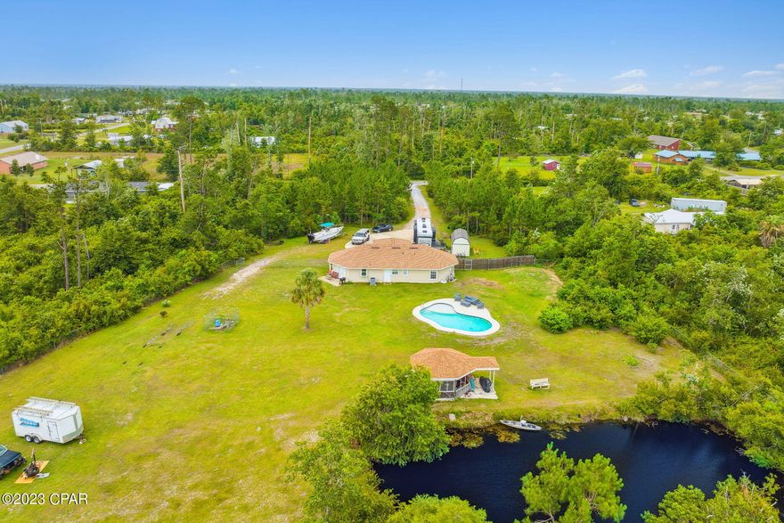 Beautifully remodeled 3 BR, 2 BA home with in-ground pool, fishing pond, and situated on over 3.8 acres! The home was recently updated with a new kitchen including stainless appliances, double oven, dishwasher, microwave, refrigerator, and quartz counters with custom cabinetry. The open concept allows for entertaining from the kitchen and a large living room. The master includes an attached master bathroom. Two additional bedrooms with shared bath in the hallway; Outdoor storage building for extra storage. Plenty of room for RV/Boat parking on the driveway slab. This is a unique opportunity to own a large acreage of land with updated home and pool located within a 20 minute drive to Lynn Haven/Panama City for restaurants, major grocers, and shopping.