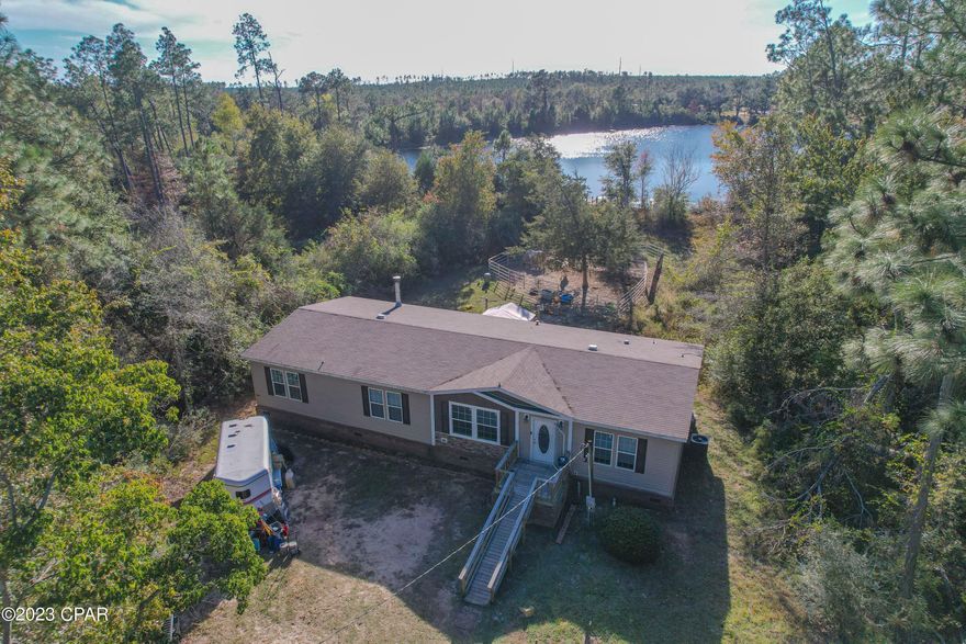 If you are looking for privacy with a country atmosphere and only 30 plus minutes from Panama City Florida, Chipley, and beaches, this immaculate waterfront home is it. This beautiful home at 2432 sq. ft cool/heated incorporates 4 bedrooms and 2 baths to accommodate a large family. Home is located in the Alford/Compass Lake area.  The Mobile home has been fully upgraded with gorgeous flooring throughout and wow factor.    Large kitchen with island and breakfast bar overlooking the living or dining room.  Additional Family room has a fireplace for those cold nights to cuddle up.  As you walk into the main entrance, you have an extra room that could be a formal living room or formal dining area. The Split Master bedroom is large with shower and garden tub. You also have a separate room for the washer and drier.  The exterior of home has all real brick skirting throughout giving it a custom look.  Back porch is covered, and you can easily access the fishing dock on your property.  Sit on your dock and watch the pristine sunset over the lake with a little fishing to relax.  The parcel is 1.13 acres with plenty of room to park your RV.  The boundaries of the property have been left alone for privacy. The many surrounding lakes to include Compass Lake, have some of the BEST fishing in Northwest Florida. Deer, Fox, Wild Turkeys all come to visit each day along with Eagles and Hawks. Sit around the campfire and share your adventures with each other. This Homesite is only minutes away from The World's Most Beautiful Beaches, Marianna Caverns, Econfina Springs, Tyndall Air Force Base, Famous Pier Park Shopping and several State Parks.