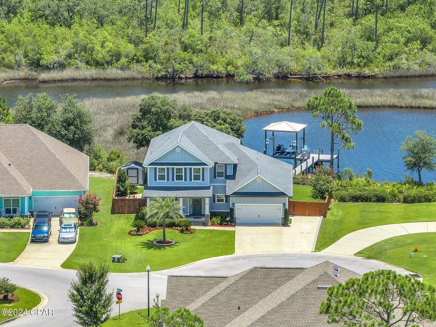 CURRENTLY UNDER CONTRACT, SELLER WILL CONSIDER BACKUP OFFERS. Check out this stunning waterfront home on Newman Bayou offering direct Gulf access! Take in the spectacular views and enjoy the incredible wildlife, including dolphins right in your backyard! Recently updated with a new roof, water heater, and remodeled primary bathroom this home sits on an ideal lot for enjoying breathtaking sunsets from your dock. The dock is perfect for fishing or jetting off to Shell Island or St Andrews Bay. The dock boasts TREX decking and currently has two jet ski lifts, but can be easily adapted for a boat. Relax in the spa room with your own hot tub. Inside, discover a spacious open floor plan with engineered wood flooring throughout the downstairs. The kitchen features newer LG appliances, complemented by a formal dining room and an eat-in breakfast area. The expansive living room is perfect for entertaining.  You'll love the tall ceilings and the abundance of natural light. The downstairs primary suite includes a luxurious remodeled bathroom with a tiled walk-in shower, separate tub, dual vanities, and a large walk-in closet with built-in shelving. For comfort and cool nights sleeping, the suite is equipped with its own mini-split AC system. Upstairs, find another primary suite with an attached full bathroom, two additional bedrooms, and another guest bathroom. Located just 22 miles from Tyndall AFB, with easy access to Pier Park (25 min), the airport (15 min), and Lynn Haven (10 min), this community offers amenities such as a resort-style pool, playground, and pavilion.