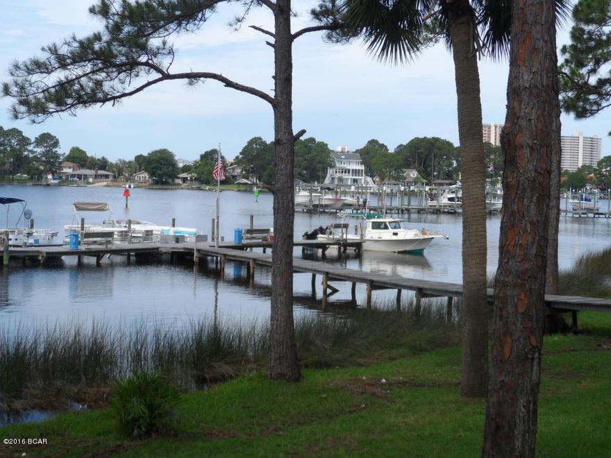 WATERFRONT on beautiful GRAND LAGOON with BOAT SLIPS available just outside your ground floor CONDO. This unit is move-in ready and NICELY FURNISHED! An upgraded kitchen includes wood cabinetry, newer appliances, and  stylish fixtures. A convenient laundry area with a washer dryer are also included. The custom tile flooring adds a warm rustic look, and makes for an easy clean up after a day on the water! The complex includes a private TENNIS COURT and POOL. The landscaping is lush and inviting. Be sure to take a look at this very affordable opportunity for LAGOON FRONT LIVING.