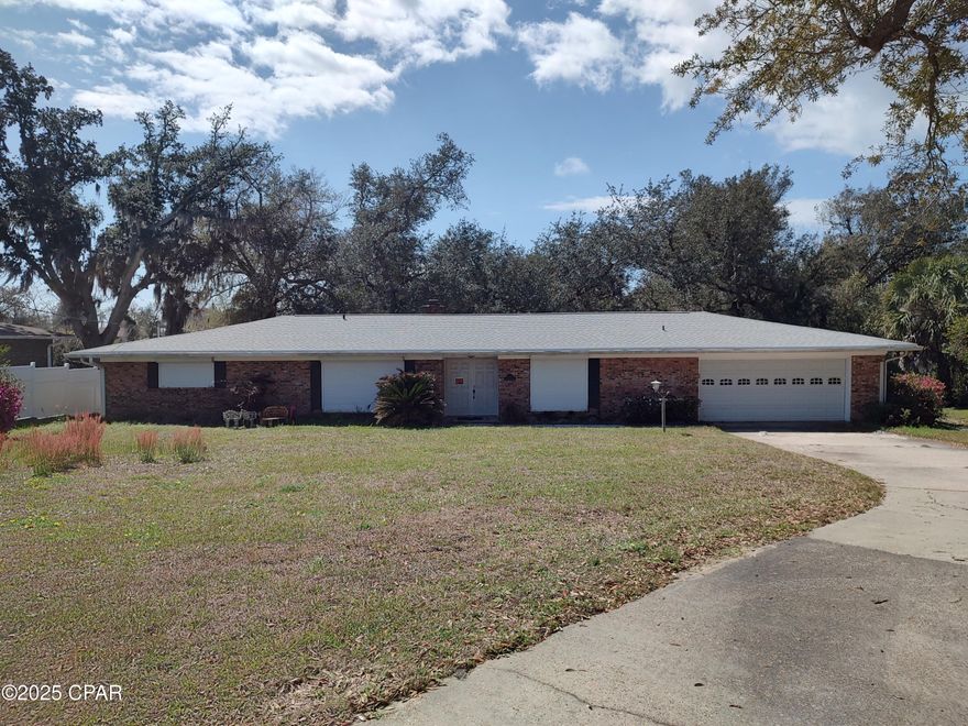 Large brick home situated on 1/2 acre lot with 100 feet lake front. Majestic oak trees shade the sloping back yard to the lake. Beautifully landscaped with mature flowers and scrubs. Plenty of concrete driveway parking for guest.  Foyer leads you into the formal living room and formal dining room continue into an open family room with fireplace, kitchen, breakfast bar, plenty of cabinets, appliances and breakfast area. Master suite features a large walk-in closet, spacious bedroom with glass doors leading to the patio. Master bath has a vanity and powder room.  Two additional large bedrooms and a full guest bath. Patio doors open from the family room onto the open patio overlooking the magnificent backyard and view of the lake.  Great features include Storm Shutters and whole house generator.   Adjoining lot available for purchase 100x257  has mature trees and flowers also.  100 feet on the lake surveys available.