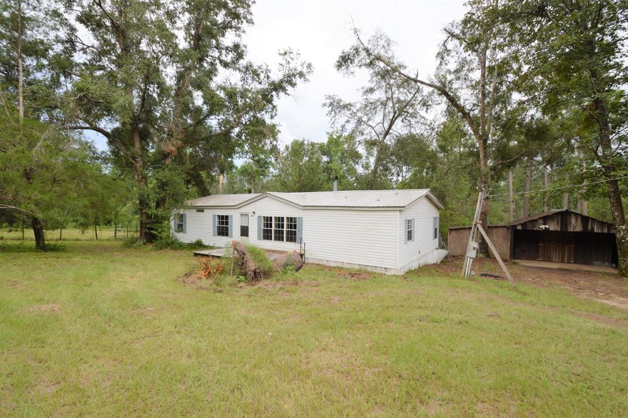 Enjoy country living with this double wide on over 16 acres down a quiet dirt road. This property features several outbuildings- one of which used to be a grist mill, a barn to keep vehicles or boats with a storage area, a cattle holding pen, fenced area for livestock, two wells, a small flowing spring, and it is mostly fenced. The home is set back off the road so enjoy a large front yard with cedar trees planted along the front for privacy. There are 3 bedrooms and 2 baths, indoor laundry room, large living room with a wood-burning fireplace, large kitchen with breakfast dining area, and formal dining room. Off the front of the home is a large deck and there is also a covered deck off the back of the home.