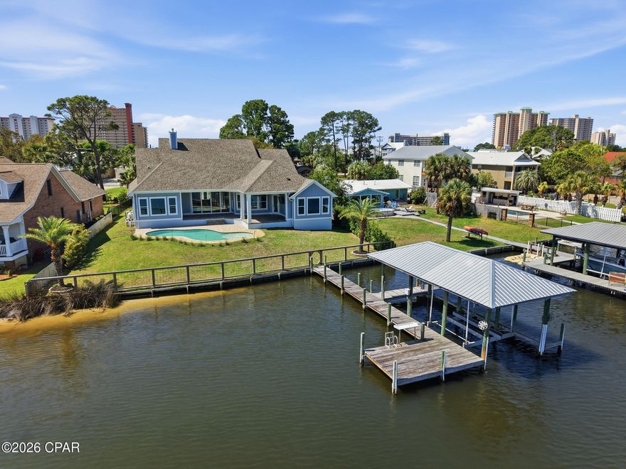 Welcome to 6728 South Lagoon Drive, a stunning waterfront retreat perfectly positioned on South Lagoon in Panama City Beach. Built in 2020 by Arthur Rutenberg, this exceptional one-story residence offers 3,404 square feet of heated and cooled living space and 4,938 square feet under roof including the outdoor living areas. An upgraded version of the sought-after May River floor plan, this home sits on a rare double lot and showcases quality craftsmanship, thoughtful design, and luxurious coastal living at its finest.

This boater's paradise offers unobstructed water views and seamless indoor-outdoor living designed to capture the beauty of the lagoon. The spacious 4-bedroom, 3-bathroom home features an open-concept layout with breathtaking views from the kitchen, dining, and living areas. The expansive living room is highlighted by vaulted ceilings, a cozy gas fireplace, and floor-to-ceiling glass sliders that open completely to a covered outdoor living space--perfect for entertaining or relaxing while overlooking the water. The dining area is filled with natural light from elegant bay windows, and the kitchen is thoughtfully equipped with a gas stove, a double oven, two refrigerators, and a generous walk-in pantry. Beautiful hardwood floors run throughout the main living spaces, while quartz countertops are featured throughout the home, with granite in the laundry room for added durability.

The primary suite is a true private retreat, featuring a split floor plan with double doors that allow you to close off the bedroom, closets, and bathroom from the rest of the home for maximum privacy. The suite also includes his and hers walk-in closets, offering ample storage and organization. The spa-like primary bathroom includes a standalone soaking tub, a marble, zero-threshold (curbless) oversized dual shower head shower, and a his-and-hers vanity--complete with a dedicated sit-down makeup area on the hers side for added luxury and convenience. The suite is also framed for a private exterior door, offering even more flexibility.

A versatile multi-use office with beautiful beamed ceilings adds character and flexibility for work or additional living space.

Step outside to your private oasis featuring a 6-foot inground saltwater pool complete with bubblers and a sun shelf. The fully fenced yard includes a sprinkler system powered by a separate well, a gated and paved driveway, and a 3-car garage with an elevated lift for easily accessible extra storage. The home is also equipped with gutters, spray foam insulation for energy efficiency, a tankless hot water heater, and a built-in monitored security system with hardwired outdoor cameras for added peace of mind. An in-wall pest control system further enhances convenience.

For boating enthusiasts, this property truly stands out with a covered boat lift, deep water dock, and seawall--allowing you to take your boat out anytime of day regardless of the tides. Enjoy a quick 15-minute boat ride to the open Gulf or take a short 5-minute drive to the area's famous white sandy beaches. Pier Park is just 20 minutes away, offering shopping, dining, and entertainment. Located in a golf cart-friendly community, this home offers both convenience and a relaxed coastal lifestyle.

With gas and electric already available for an outdoor kitchen, this home is ready to create the ultimate waterfront experience.

Don't miss your chance to own this exceptional coastal property where luxury, comfort, and breathtaking views come together.