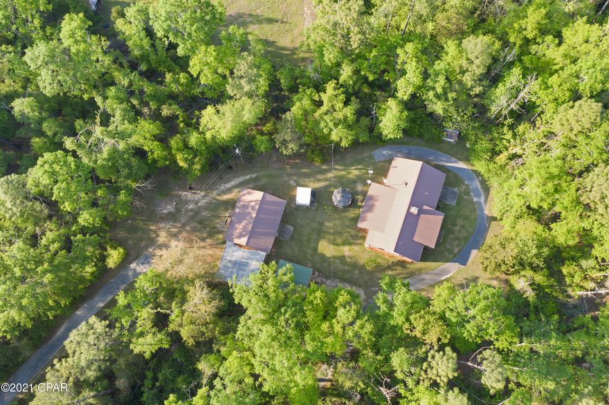 CURRENTLY UNDER CONTRACT, SELLER ACCEPTING BACKUP OFFERS. Stroll down the paved circular driveway into your own private haven. The 6.9 acre property features a one-owner brick home, an 880 sq. ft. workshop w/attached carport, gazebo, storage shed w/concrete foundation, and a detached carport. The home offers a 50 year metal roof installed in '98, attached garage, screened back porch, wood-burning fireplace, master double vanity, brand new washer, storage room in the garage which was also used as a safe room. The home is already wired for ADT and has an existing termite bond until 4-30-21. The workshop has electricity, half bath, automatic garage door, attached carport w/slab, +work benches. Jackson Branch, which runs into Holmes Creek, runs behind the property creating a small Cypress Pond Only a small portion of land is cleared for maximum seclusion. Here you really feel away from it all. The home is dated, but is a one-owner in great condition and has been meticulously maintained throughout the years- what an opportunity to be a second owner! The paved driveway cost was $22k and is actual pavement. A new well was drilled in the last 10 years and the a/c was new in 2011. The gate leading into the property is automatic. This home is ready for its next chapter!