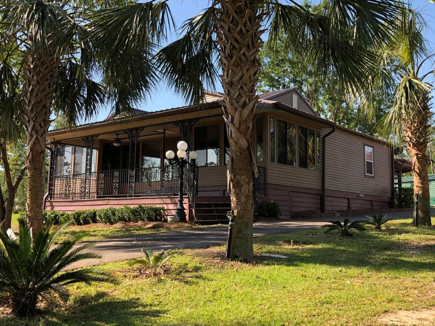 Tropical Oasis Setting in this Lake McCormick water view home has it all. Home has 2/2 but was used a 4 bedroom.  Large open kitchen / great room gives great family time.  Large porches front and back. Big utility room, Paved driveway lined with beautiful Palms trees.  Screened Gazebo, flower garden, RV Bldg with new roof , 30 amp service separate, several storage buildings.  home sits on over 3 acres, fig trees, scuppernong grapevine, water available in many locations through out the yard.  Back entrance from another street with workable traffic light. Lots of love and thought went into this.  Gated front and and back entrance. Plenty of room for another home site with spectacular views of the Lake. Make an appt. today!