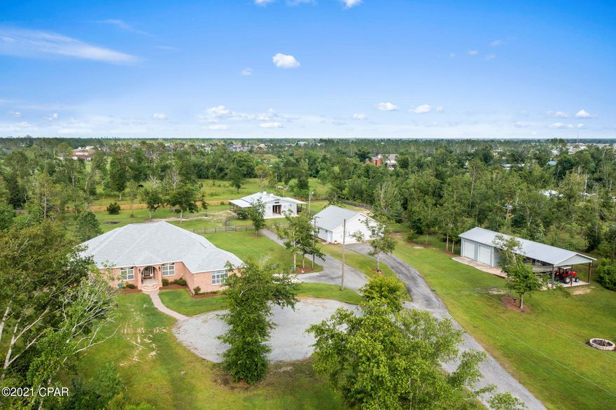 Country living close to town and beaches: drive through the lighted brick columns with large black gates to your oasis -  4 bedroom/3 full bath all brick custom home with inground fiberglass pool and spa on 5.54 acres. Cathedral ceilings in great room with gas fireplace. Transom windows throughout home allow for lots of natural light.  Home has two master bedrooms both with french doors leading to the pool deck, the largest being a split plan with ensuite and two walk in closets. Master bath has granite counters with dual sinks, solid oak custom cabinets, double walk in shower, jetted large tub, and separate makeup vanity. The second master has a walk-in closet and ensuite bathroom with granite countertops, custom solid oak cabinets, dual sinks, tub/shower combo along with french doors to the pool deck. The 1600 sq ft workshop is plumbed for a bathroom, has a double car garage, side door entry, and new architectural shingle roof. The workshop could be a mother-in-law home or recreational room. The custom 5 stall horse barn has Priefert stall fronts each with hay and feeding doors, indoor wash bay with hot water heater, separate tack room, and separate feed room. Each stall has custom dutch doors. There is also a lighted arena for riding. Trailer and boat covered storage with three open bays and two enclosed bays with roll up doors for storage. Kitchen is equipped with solid oak custom cabinets, granite counters, stainless steel new appliances. Indoor large laundry room also has custom solid oak cabinets and granite counters. Third bath has custom cabinet with granite counters, large shower and opens to the pool deck. Custom plantation shutters and crown molding throughout this lovely home along with new architectural shingle roof, new HVAC and new flooring. Kinetico water system and 2 hot water heaters. New well tank. Open floor plan allowing for a great entertaining space and large great room wired for surround sound. Covered lanai across back of home with granite bar overlooking inground pool and spa. The property features a pond with a rock design waterfall and is located at the end of a dead end road backing up to over 2000 wooded acres. An additional 3+acres adjoining the property is available for purchase for a total of 8.4 acres. Only 15 minute drive to downtown and less than 1 mile to the Deerpoint boat ramp. Be in fresh or salt water in a jiffy. Don't miss out on this lovely estate.