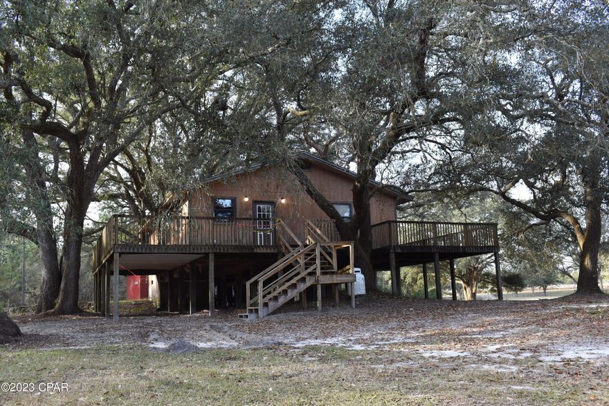 With some TLC this would make a PERFECT camp house with easy access to lakes, rivers, ponds, state parks, and only minutes away from the Northwest Florida Beaches International Airport, Panama City Beach and Pier Park with shopping galore!!!!!!
This 2BR/1BA home is on stilts with a porch/deck on three sides and has a lot to offer. 
A nice spacious kitchen with lots of cabinets, with an adjoining dining room, an oversized living room with access to the porch, an office/den with access to the porch, a large bathroom w/ utility room for convenience to wash and dry clothes and two spacious bedrooms with one having access to a separate porch for relaxing under the trees. 
Outside the home is surrounded by beautiful HUGH majestic oak trees and several outbuildings.  
There is also a small pond that with irrigation could be easily filled with a variety of fish.
ALL OF THIS IS ON 7.1 ACRES OF BEAUTIFUL LAND!!!!!!!