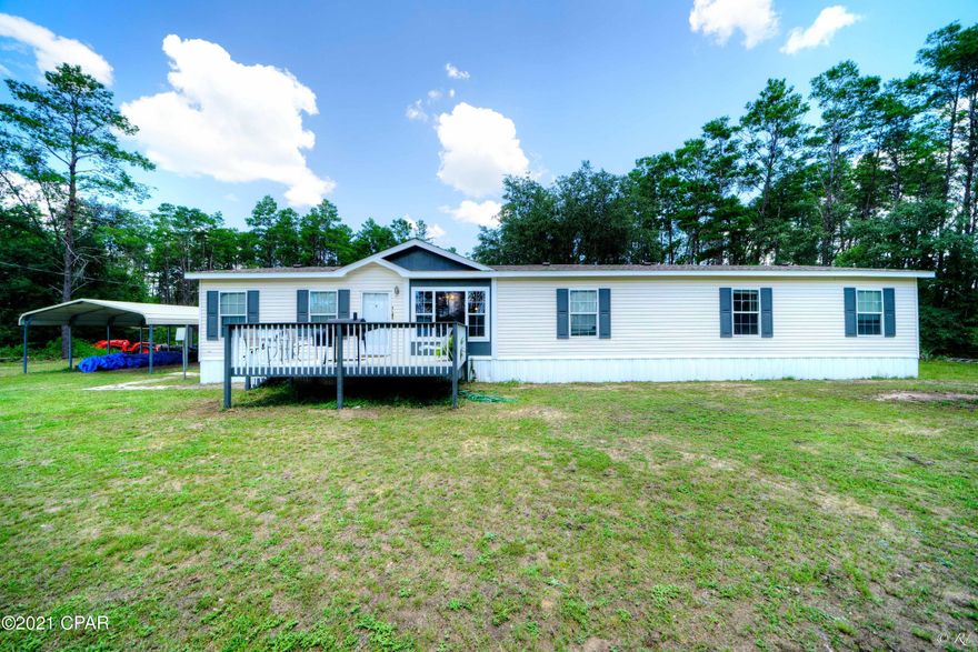 This double wide mobile home with 4 bedrooms and 2 bathrooms is located on nearly 5 acres of land in a quiet neighborhood away from the city.  This home features a large and inviting front porch which leads you into an open sitting room with brand new LVP flooring and new paint throughout. The kitchen features a breakfast bar, a pantry, and honey-colored wood cabinets. The large master bedroom is equipped with a huge walk-in closet and French double doors that open to its own private ensuite.  The master bathroom features a soaking tub, two separate vanities, and an additional room with a toilet and stand-up shower for your convenience. The open den area features a wood-burning fireplace perfect for enjoying the colder nights with family and friends. The additional bedrooms share a bathroom that is equipped with a shower/tub combo and tile flooring. This home also features a carport, a shed for extra storage, and a large flag pole which all conveys with the purchase. This home is located near parks, fishing spots, and schools for your convenience.