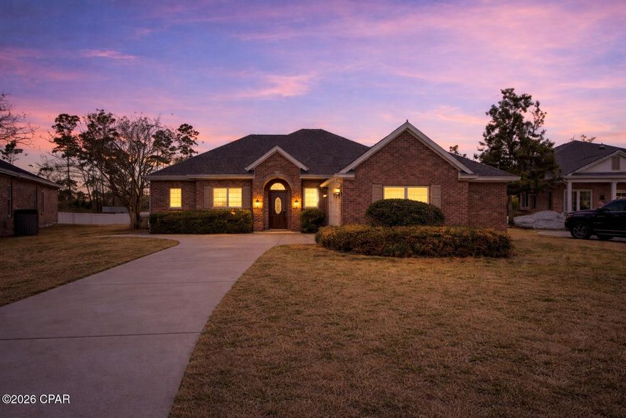 Positioned on a private cul-de-sac lot in the prestigious Hawks Landing community in Panama City, this substantial all-brick 5-bedroom, 4-bathroom executive residence offers 3,605 square feet of thoughtfully designed living space backing to a wooded buffer for added privacy. Built in 2007, the home combines durable construction with generous proportions and architectural detail rarely found in this price range.

Ten-foot ceilings throughout the main level and nine-foot ceilings upstairs enhance the sense of openness and scale. Crown molding, arched openings, and decorative columns add timeless character, while genuine hardwood flooring anchors the primary living areas, complemented by ceramic tile and carpet in designated spaces for comfort.

The main living area offers exceptional gathering space centered around a gas fireplace with built-in shelving and views of the private backyard. The kitchen provides granite countertops, stainless steel appliances, abundant cabinetry, recessed lighting, and a raised breakfast bar that opens seamlessly to the living space, making it well suited for entertaining or larger households.

The oversized primary suite serves as a private retreat with dual granite vanities, a corner jetted tub, and a separate glass-enclosed shower. Four additional bedrooms and multiple full bathrooms provide flexibility for guests, office needs, or multi-generational living. The upstairs bonus room with full bath access adds valuable separation, ideal for a media room or private guest suite.

The covered rear porch extends the living space outdoors and overlooks a backyard with no immediate rear neighbors. The irrigation system operates on reclaimed water, and utilities are serviced through the City of Lynn Haven.

Located within walking distance to Bay Haven Charter Academy and A. Crawford Mosley High School, and convenient to grocery, dining, and retail amenities, this property offers both space and accessibility in one of Panama City's most established neighborhoods.