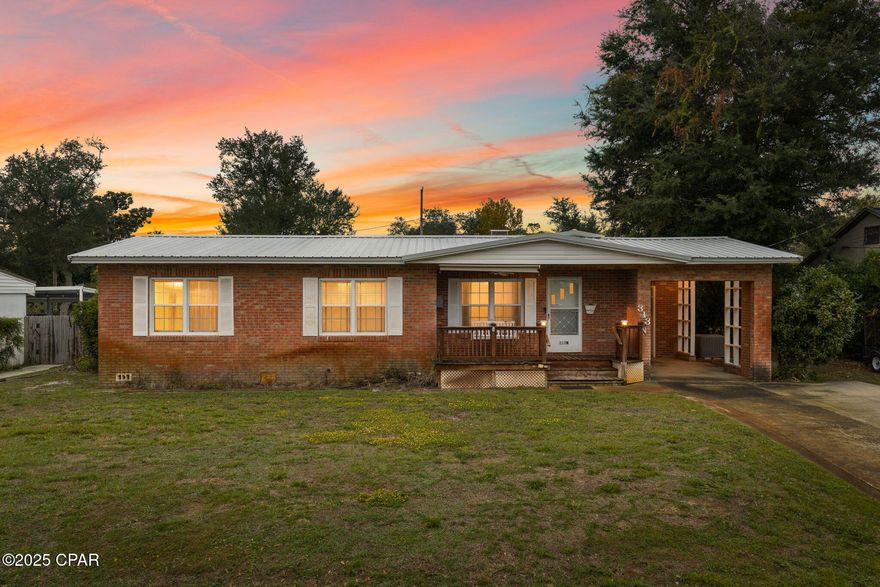 Located in The Cove, one of Panama City's most established neighborhoods, this classic brick front home offers timeless character paired with thoughtful updates. A charming front porch welcomes you inside, where original hardwood flooring flows through most of the home including the bedrooms, hallway, and formal living area. The layout includes 3 bedrooms and 1.5 bathrooms along with both a formal living room and a cozy family room featuring a brick gas fireplace. The large eat in kitchen with a built in desk provides a functional hub for everyday living.

A whole house generator powered by natural gas and a metal roof installed in 2019 add peace of mind and long term value. Practical features include a walk in pantry, a separate utility room with space for a freezer, and a partially floored attic for extra storage.

Outdoor convenience includes a 1 car carport, additional driveway parking, and alley access that is ideal for a boat, small trailer, or recreational equipment. The backyard includes a powered workshop with AC as well as a lawn irrigation system serviced by a deep well.

The Cove's golf cart friendly streets and close proximity to Bay Medical, local schools, churches, and downtown Panama City support a convenient coastal lifestyle. Enjoy waterfront parks, marinas, dining, shopping, and year round community events all minutes away. This home offers a blend of historic appeal, everyday comfort, and desirable location.

Buyer to verify all important information including measurements, utilities, and features. Porch swing does not convey.