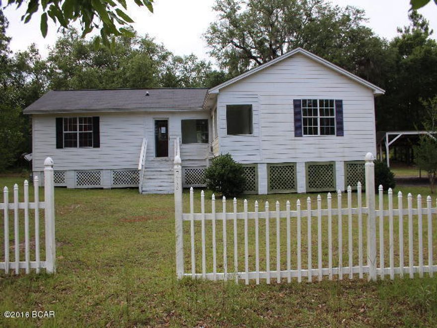 PRICE REDUCED!! Lovely home in the country with white picket fence. Comes with 3 car detached carport with an attached shed/building. The home features a split bedroom design with large master and bath on east side with door that opens up onto enclosed sitting sunroom/porch area. There is a rear deck that overlooks back yard with beautiful massive oaks! All of this is situated on 2.18 acres. Nice property!!
