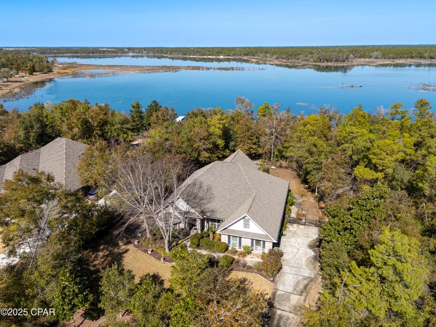 Welcome home to this exceptional lakefront residence prominently situated on Lake Merial. This stunning brick home has been meticulously maintained and upgraded with all the finest features. From the soaring double tray ceilings to the high-quality flooring, nothing was overlooked from top to bottom. Upon entering, the study to the left has built-in cabinetry, a large bay window, and added French doors for privacy. The spacious, open-concept living area provides plenty of room for oversized furniture and hosting gatherings. There is both a formal dining room plus a breakfast table space, not to mention the kitchen with custom cabinets, stainless appliances, granite countertops, and a pantry for additional storage. The HVAC was recently replaced for peace of mind. 
Adjacent to the living room, the previous patio was enclosed to make a cozy sitting room. This adds to the existing home size to make it a grand 2756 sqft. The generously sized primary bedroom features windows overlooking the lake, both a tiled shower and a tub, a double vanity, and a large walk-in closet with built-in shelving. On the other side of the home sits the second bedroom which also features lakeview windows, a second bath with custom tile shower, plus a third bedroom currently being used as an office. As if that weren't enough, there is an upstairs flex room above the 2-car garage that could be utilized as an additional bedroom, hobby room, or storage space. Finally, added to the rear of the home is the incredible Florida room with a tongue and groove vaulted ceiling, floor-to-ceiling windows for the lake view, and a grill hood for ventilation while grilling. This single-owner home is truly a masterpiece and a must-see. 
Situated on a hilltop on a unique, approximately 1-acre lot, there is plenty of exterior space to install a pool. The property is adorned with mature trees that provide additional privacy and a more secluded feel. There is an open paver patio and backyard with wrought iron fencing. As an added touch, the seller requested that the pavers be continued down a winding path to the lakefront where there is a two-tiered flat area of pavers by the lake - perfect for comfortable outdoor chairs, a beverage, and tranquility. There is additional wrought iron fencing before the lake's edge.
Lake Merial is a gated community that is highly esteemed and enjoys nature-based amenities. Residents enjoy enhanced privacy, scenic walking trails, a picnic area, and access to the pristine 300-acre spring-fed lake. Enjoy fishing, paddle boarding, kayaking, and other water activities right in your backyard. Located only 20 minutes to Northwest Florida International Airport, 20 minutes to Lynn Haven shopping and dining options, and 30 minutes to the emerald waters of Panama City Beach, the location is especially convenient. This home is priced to sell and ready for its next owner. Schedule your showing soon.