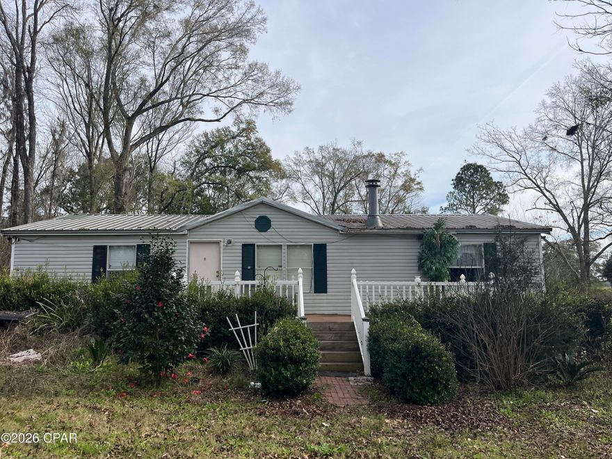 Set on 2 fully fenced acres, this 3-bedroom, 2-bath mobile home offers an incredible opportunity for those seeking a homestead-style property with room to grow. While the land is in need of a little care, the foundation for a productive and peaceful lifestyle is already in place. Each bedroom features a walk-in closet, and the living area includes a wood-burning fireplace, perfect for cozy evenings after a day spent outdoors. The front deck was redone just two years ago, providing a solid spot to enjoy your morning coffee surrounded by nature.

The land is thoughtfully laid out with second fenced-off section, making it ideal for animals, gardens, or rotational use. An older chicken coop and dog pen are already on the property, and a lawn mower and chainsaw convey, helping you bring the land back to life. For added peace of mind, six security cameras will remain with the home.

This property truly shines in its established plantings and fruit trees, a rare find for homesteaders. The land features Banana trees, Japanese and Red Magnolia trees, Sago palms, Pink Roses, fresh mint, Blue Hydrangeas, Azaleas, and multiple Pecan trees. Fruit-bearing plants include 3 Peach trees, 2 Pear trees, 3 Fig trees (including a yellow fig), Plum tree, Pomegranate tree, Persimmons, Blueberry bushes, Apricot tree, Yellow and Red Cherry trees, and a Lemon tree. Some plantings are currently in need of attention; but with time and care they could flourish into a productive, beautiful landscape.

The back portion of the property includes fallen trees and brush, offering an excellent opportunity for clearing, firewood, or future expansion. Whether you're dreaming of a self-sustaining homestead, hobby farm, or peaceful country retreat, this property provides the land, layout, and potential to make it your own.

Furiture being sold separately.