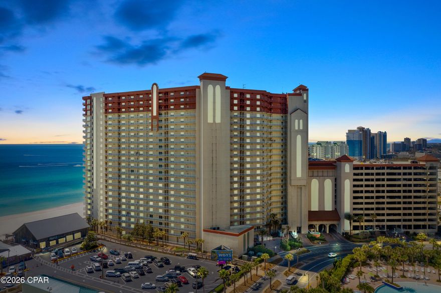 WRAPAROUND CORNER BALCONY | HIGH-FLOOR GULF, POOL, AND COASTLINE VIEWS |
DEEDED PARKING ON THE 8TH FLOOR ATTACHED GARAGE | Shores of Panama Unit 2003 is a 20th-floor corner residence featuring the desirable Type E floor plan with two bedrooms, two full bathrooms, and a bunk room with an additional half bath. Positioned on the west-side corner of the building, the wraparound balcony captures expansive views of the resort lagoon pool, the Gulf, and the Panama City Beach coastline in both directions. The elevation and corner position also create exceptional sunset views. The primary bedroom is located on the Gulf side with direct balcony access, allowing water views from both the bedroom and the main living area. The kitchen has been fully remodeled with new cabinetry, quartz countertops, stainless steel appliances, and a distinctive blue mermaid tile backsplash. The interior presents a clean, modern look with consistent flooring throughout the unit, updated light fixtures, ceiling fans, and rolling shades installed on all windows and glass doors. Both bathrooms have been updated with walk-in tile showers and glass enclosures. The unit also includes a front-load washer and dryer. A deeded parking space on the 8th floor of the attached parking garage adds convenience and allows direct building access without crossing the street to a separate parking structure. Shores of Panama Resort features the largest Gulf-front lagoon pool in Panama City Beach. The zero-entry tropical pool includes palm-lined islands, fountains, and a spacious hot tub set along the resort's private beachfront access. Additional amenities include an indoor heated pool and hot tub, a 24-hour fitness center, and a seasonal poolside Tiki bar. The resort's central Panama City Beach location places dining, shopping, and entertainment nearby. Pineapple Willy's is adjacent to the property for beachfront dining. Laketown Wharf, directly across the street, offers Juan Taco, Wharf Seafood Buffet, The Candymaker Ice Cream Shop, PCB Pizza, In Cahoots for breakfast and brunch, The Press coffee shop, The Bun Lab, 810 Billiards & Bowling, a salon and nail bar, and additional retail options. Nearby attractions include Dolly Parton's Pirates Voyage Dinner & Show, Topgolf, and McGuire's Irish Pub, with Tootsie's Orchid Lounge scheduled to open in 2026 as the area continues to see new entertainment and dining investment. HOA dues are $4,354.06 per quarter. All information is believed to be accurate but should be verified by buyers if important.