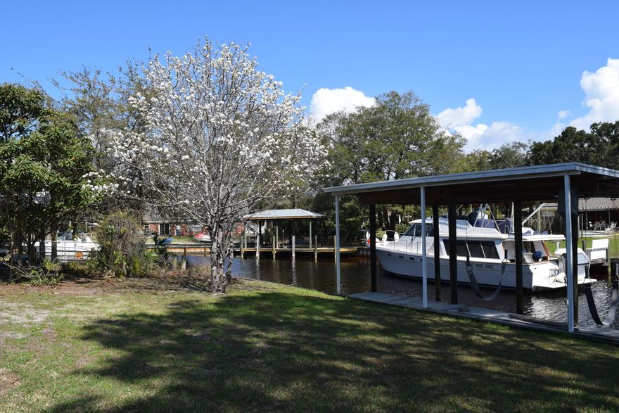 Large, deep, waterfront canal home with seawall and dock, covered RV/boat port on a concrete pad, over sized two or three car garage, and lots of driveway-all located on a cul de sac. This home and the large fenced in lot has much to offer a growing family. Right in your own backyard enjoy the best of fishing, boating and freedom! No HOA! Bring all the toys you want! This large, two story home with two master suites on the ground level has an extremely attractive split floor plan. Each family member can pretty much have their own turf within this large home! The sizable living room has a 16 ft ceiling and wood burning fireplace. The whole downstairs is tiled for easy maintenance and the interior was freshly painted with all neutral paint. Downstairs has 3 bedrooms, two of which have on suites and lots of extra storage. The master bedroom has two sizable walk in closets. The backyard has a covered porch, double gated access, making it easy to maneuver trailered boats, lots of open and paved walks and open patio areas. There is a yard building for additional storage. All structures have metal roofs. The landscaping is mature and beautiful. The well system is 360 ft deep and  about 10 years old. Per owner, the home was built up 9ft above sea level and is covered under a termite policy with Gulf Coast Pest control.