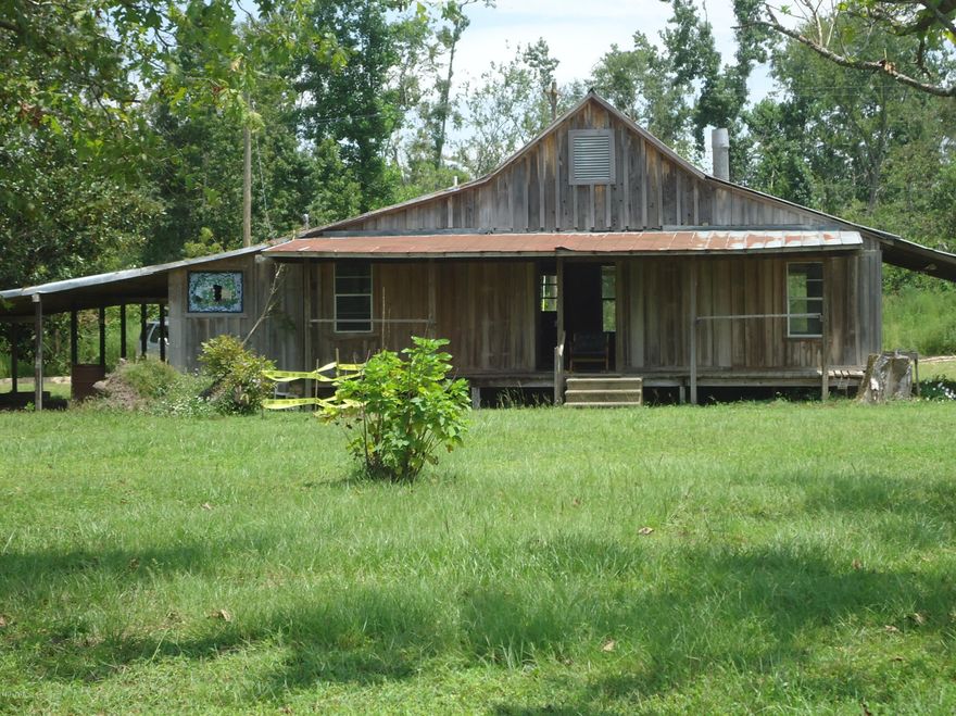 Beautiful Country Setting.  Board and Batten frame home that you can finish to make your home/cabin in the woods.  Needs to be COMPLETELY done on the inside but has nice front and rear porches and a small pond. It sits by the rail road track.  It would make perfect starter home or a great little cabin.