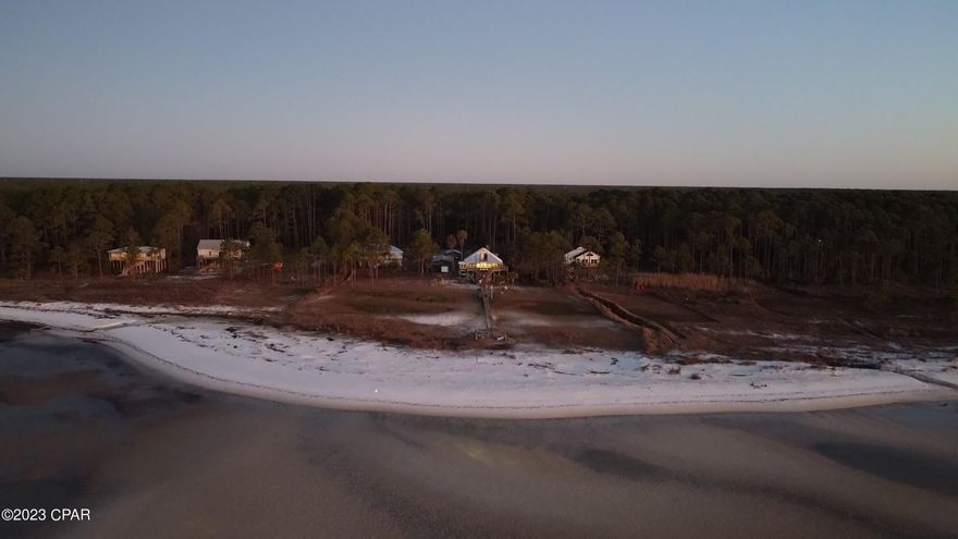 Discover the Forgotten Coast and its old-Florida nostalgia in this 3-bed, 3-bath, waterfront dream, tucked away in the quiet coastal town of Carrabelle. Upon entry, you'll immediately be struck by unparalleled views of private beach and St. George Sound. The beautiful tongue and groove ceilings and wood floors add to the rustic charm of the property, creating a warm and inviting atmosphere. Between the loft bedroom balcony, 3 sunrooms, and the end of the dock, it'll be hard to pick your favorite spot for sunrise.



The 3 outbuildings, each with electrical, provide plenty of space for your hobbies, while the three carports are perfect for covering cars, boat, RV, and tractor. Whether you are looking for the perfect retirement property, a weekend getaway, or rental property, look no further One of the most unique features of this property is that it's growing! Through the process of accretion, the beach has slowly grown through the years. Since the owner bought the property in the 90s, the waterline has gone from the middle of the dock structure (where the American flag is), all the way past the end of the pier.