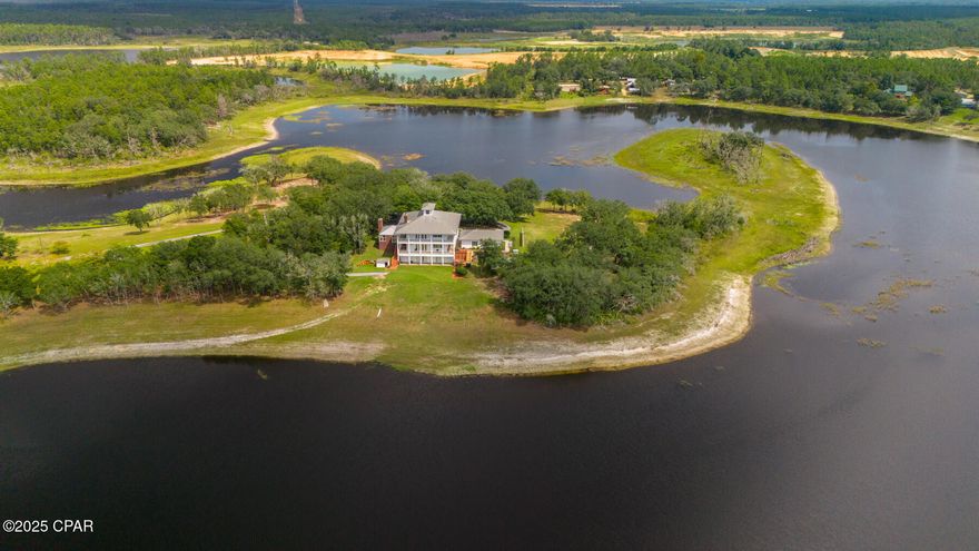 INCREDIBLE lakefront estate on 32 Acres with 360° Water Views! Nestled just north of Panama City, Florida, this extraordinary 32-acre estate on freshwater River Pond is a remarkable gem. As you enter this lakefront estate, you're greeted by a scenic 100+ year oak tree-lined road leading you to a stunning 7,200 sq. ft. Southern-style home, perfectly positioned on the end of a peninsula offering breathtaking 360-degree lakefront views. Additional acreage available for sale with purchase. 

Designed for both luxury and function, this 5-bed, 5-full bath, 2-half bath residence boasts show-stopping wrap-around porches on all levels, mother-in-law suite, & incredible 10-foot ceilings throughout all three levels. Two upper levels at 4,000 SF, walk-out basement at 2,000 SF, heated/cooled storage at 1,200 SF. Enjoy the ease of access with a full-size elevator, making every part of this home effortless reachable.

As you step into this Southern retreat, you're greeted with a formal dining room and spacious sitting room that would also be great for a home office. This home exudes timeless charm and modern luxury. Enter through the foyer and your eye is drawn directly to the French doors leading onto the covered porches where you'll enjoy impressive lake views and exceptional sunsets year-round. 

The main level of the home features an expansive chef's kitchen with quartz countertops, adjacent bar and a walk-in pantry. A cozy fireplace anchors the living room and is enhanced by French doors leading to stunning waterfront views. This main level also provides direct access to the screened-in summer kitchen designed for seamless indoor-outdoor entertaining. A powder room is also found on this level.

The upper level of the home features a spacious primary retreat with a walk-in shower, soaking tub, double vanities with ample counter space and custom walk-in closet. This level also hosts the laundry room, two additional bedrooms and two baths and direct access to the covered porches on the front of the home overlooking the gorgeous oak trees. 

The lower level of the home is a true walk-out basement but don't let the name basement fool you. This level has 10' ceilings just as the two upper levels and features a full kitchen, spacious kitchen island, living room with fireplace, home theater room made for entertaining, and two additional bedrooms and two bathrooms--making the ideal setup for guests or multi-generational living. Access to the covered porch is just off the living room area through French doors and you're just steps away from the shores of the lake. The lower level also provides an expansive 1,200 sq. ft. heated & cooled storage room--perfect or storing hunting & fishing gear or for crafting & hobbies. 

Next to the home you'll find a detached 3-car garage for ample storage and parking along with a circular driveway for easy access of multiple vehicles. The ultimate outdoor paradise is what you'll call this retreat. This freshwater lake is ideal for fishing, tubing, and water skiing, offering a serene and secluded lifestyle just 20 minutes from town. With plenty of space for ATVs, side-by-sides, and outdoor adventures, this is a true country retreat, designed for families to grow for generations to come. 

Built solid with poured concrete construction, this fortress of a home on the lakefront is as durable as it is breathtaking, with classic white horizontal clad siding and red brick accents completing its timeless Southern charm. As you sit on the porches from all sides, you're mesmerized by the shade the stunning oak trees offer and the charm that Spanish moss provides. This property has been impeccably maintained by its original owner and no detail has been left untouched. Remarkable landscaping spans the entire property so you can enjoy every aspect of this lakefront retreat. 
Don't miss this rare opportunity to own a luxury waterfront estate encompassing the entire peninsula!