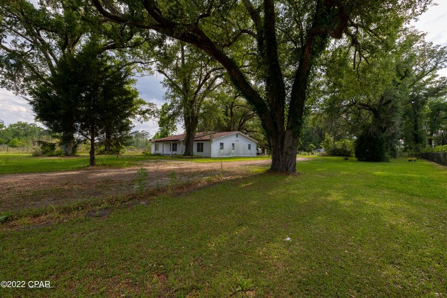 'CURRENTLY UNDER CONTRACT, SELLER WILL CONSIDER BACKUP OFFERS Beautiful Live Oak trees adorn this homesite - a fenced area and stable for farm animals (currently used for goats) and a chicken pen make this an ideal hobby farm site. Home is being sold As Is - with repairs and TLC this home will be a spacious treasure for a family wanting to live in the country but convenient to PCB or I10.  This home is 35 miles to ECP, 36 miles to Pier Park, 10 miles to I10 or .2 mile to Holmes Creek and several public boat launches within a few miles.  The home needs updating and repairs to the AC and one of the bathrooms.  The large kitchen and pantry are ideal for canning.  The home hosts 2 large family rooms and a dining room - wallpaper is nearly all removed