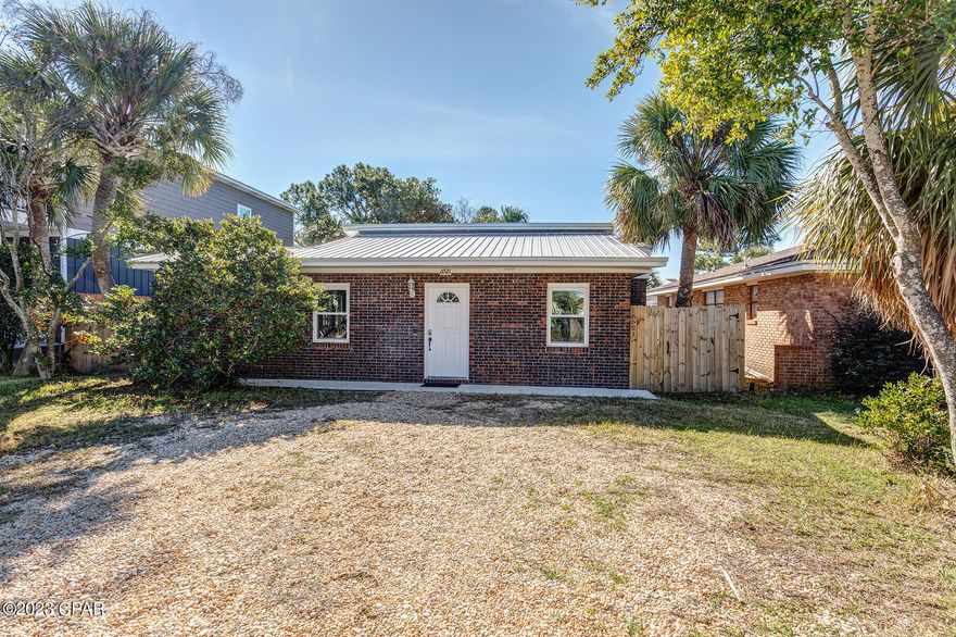 This 3 bedroom/2 bath brick home has so much to offer and is situated along the beautiful Lagoon front community on Panama City Beach that is South Lagoon Drive. The area is an eclectic mixture of year round home ownership, to the occasional second home visitors, as well as short term vacationers. Remodeled in 2021, from drywall & fresh paint to an entire new kitchen, bathroom cabinets, granite counter tops & faucets, to new interior doors and new wood like floor tile throughout the home. The metal roof and all windows were replaced in 2020.  Includes new stainless appliances, washer, & dryer. As you first walk into the home, you will notice the stone facade from floor to ceiling surrounding the fireplace. An electric insert in the fireplace adds ambiance & some heat The open floor plan of the kitchen and living room area are enhanced even more by the vaulted ceilings and large windows over the kitchen sink, bringing the outside light into this space. One of the guest bedrooms has a sliding glass door for access to the backyard. The large hall closet offers ample storage and a barn door for ease of access. The tile floors throughout the living area, kitchen and bedrooms have the wood look without the maintenance and upkeep of wood.  Outside in the large privacy fenced backyard, you have a large brick paved patio with outdoor hot/cold shower for entertaining. There is a 12x24 ft air conditioned workshop/storage shed. Brand new TRANE A/C installed in Sept. 2022. New metal roof & vinyl windows were installed after Hurricane Michael. The neighborhood is golf cart friendly as well. There is a transferable Termite Bond. The seller would entertain leaving any furniture for someone that wants to turn the property into a vacation rental opportunity. The beach access is within .6 miles to beach access 12A.  Rick Seltzer Park is only .8 miles. St. Andrews State Park is 2.4 miles and Pier Park is 7.7 miles.
