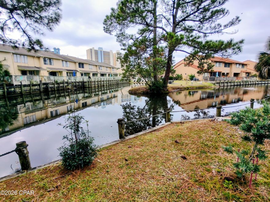 Do you want to WALK TO THE BEACH from YOUR HOME? Come check out this 2 Bedroom with 2.5 Baths. It is a ''Glassback''style unit backing up to the CANAL. This unit has a lot of Property in the Front & Back of the unit. If you are L@@king for a unit to sit out back and Enjoy your Coffee, Grill Out, or Read a Book come check me out.  If you enjoy Peacefulness you will love Sitting out by the Canal on this private Dead End Street. You can even invite friends to visit and have plenty of Entertaining Space and if they spend the night they can have their own Private Bath. Bring your toothbrush and clothes and start enjoying the BEACH today!!! This unit has 2 Private Parking Spaces, so if you get a ''Street Legal'' Golf Cart, you will have a place to park it and you can CRUISE to Walmart, St Andrews Park, Pier Park, Post Office, Shopping, Dining, and THE BEACH. The Post Office, Walmart, and THE BEACH are in WALKING DISTANCE. HOA fees are $1122.24/Qtr and include Household Trash Disposal, Wi-Fi Internet, Lawn Mowing, Sprinklers, Termite Contract with HOA, Some Pest Control, and the Amenities... 11 Pools ''5 Heated'', 3 Tennis Courts ''2 Lighted'', 4 Pickleball Courts, Fitness Center, 18 Hole Mini Golf, 2 Playgrounds, Shuffleboard Courts, Conference Center, and a Private Beach House with a Snack Bar on The Beach along with 1 of the 11 Pools. ~~ 
Age, S/F, and Dimensions are approximate... Please verify if important. ~~
All Information contained herein is deemed to be reliable but not guaranteed and should be verified by the Buyers. Everything is subject to... Errors, Changes with items in or on the Property, Omissions in prior sales, changes or withdrawals without notice.