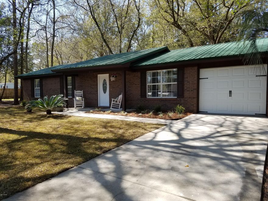 New!  An Amazing all brick home on over an acre! This home has been transformed. It is tastefully updated and priced to sell. An open concept floor plan and tons of natural light make this home bright and airy. Stunning Lumbermill Oak floors in all main rooms. The kitchen is breathtaking. Beautiful satin white cabinets, granite countertops, and glass subway backsplash. Brand new Whirlpool stainless steel appliance package and tub style sink with window overlooking views of the wooded property. Huge breakfast bar and formal dining space. This floorplan is perfect for families or entertaining friends. Entire home shows as new. Both baths are spacious and have beautiful vanities, marble countertops, and 24x12 porcelain tile floors. All bedrooms are nice sized and have new carpet. It is truly built to last with all brick construction and a metal roof. No flood zone on this property, it is very high and dry. Nice workshop, beautiful magnolia trees, palm trees, and hardwoods. Schedule your visit today!