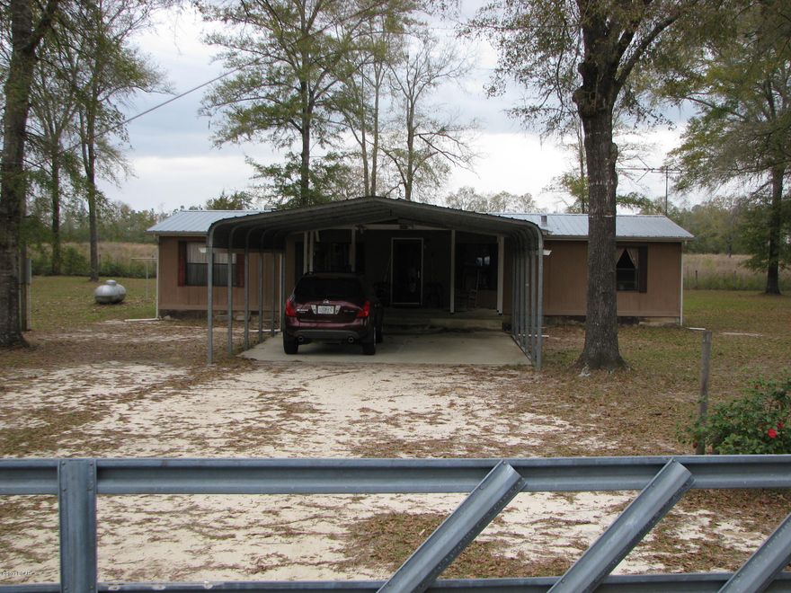 Don't miss this unique mobile home, on a totally fenced in 2.08 acre lot. It features a covered carport that leads right to the front of the house. On the back of the house there is a large screened in porch with two utility areas (a freezer that comes with the mobile home). There is an equipment shed on the property, a covered RV shed, and another small metal shed. It is a split bedroom plan with the master and master bath on one end and the two additional bedrooms and bathroom on the other. It has two living spaces and is open floor plan. Would be a great place for retirement or first time home buyers. The yard would be perfect for pets or kids. (Lot dimensions are estimated but it is 2.08 acres.)