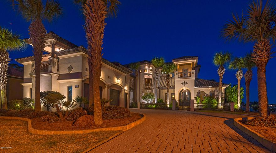 Mediterranean design complemented by Old World elegance will instantly grab your attention in this beautiful waterfront residence. Upon entering, you are greeted by breathtaking 11 foot iron doors. As you pass through the archway into the foyer, you will then embrace the shimmering water of Grand Lagoon. This home blends rustic comfort with casual elegance. Design elements of travertine, stone, copper, tile, wood and mosaics, Corinthian columns and coffered ceilings are artfully orchestrated throughout the home. To your right as you enter is the guest suite which includes a walk thru closet and bath with a steam shower- the vanity is a sacrament piece from a historic church, and an exercise room overlooking the lagoon. The living room includes a double side fireplace, which graces the living room and family room, a custom bar with a copper top, a finished wine cellar and built in cabinetry including a 19th Century ships door. Reclaimed from Lake Michigan, wide plank Heart pine floors and Old Chicago brick archways take you into the heart of this home which also includes the incredible view of Grand Lagoon. The kitchen boasts all of the essentials to preparing a gourmet meal. The dining room and family room also overlook the backyard, lagoon, pool and hot tub. The family room comes complete with a built in entertainment center and computer desk. The outdoor kitchen will be a chef's dream, featuring a custom made wood burning and gas brick oven, professional gas grill and granite countertops. Continuing up the wrought-iron staircase to the next level, you will enter the media/bonus room over the 3-car garage. The bonus room includes a full bath with shower, built-in media center, wet bar, 2 bunk rooms, and room for a pool table (included). Walking up to the next level of the home you will pass the Juliette balcony overlooking the front yard. On the left is a large laundry/craft room with built in cabinets and granite counter tops. Down a slightly elevated hallway on your right are 2 additional bedrooms with full baths and walk in closets, each room featuring its own balcony. At the back of the home overlooking Grand Lagoon is an executive office with a two-sided desk and custom cabinetry. The master suite is adjacent and includes a large bedroom with a tray ceiling, balcony shared with the office, and a sitting area overlooking the spectacular view of Grand Lagoon. The master bath includes double raised sinks, Jacuzzi tub, open dual shower, and walk in closet with custom cabinetry and a hidden door to the laundry room. The home also includes a 3-car garage with a workshop.The dock includes boat slip and boat lift. This mediterranean interpretation of Old World design makes the home a lovely and unique example of Florida coastal living. All info is approximate please verify if it is important.