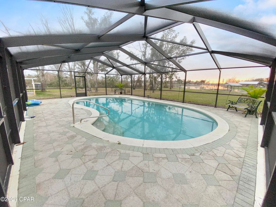 Waterfront, on 3 acres with pool and workshop! Do I have your attention yet? This  2400+ sq ft 3 bedroom 2 bath waterfront home sits beautifully on 3 acres with an inground screened pool, a dock and a heated and cooled workshop! Location is everything and this property is one of a kind, It's in a quiet neighborhood, close to town and NO HOA! The home offers an open floor plan and space to spare! You'll LOVE the water view from the master bedroom and the split floor plan with large, roomy additional bedrooms.  The beautiful wood flooring in the kitchen is a wonderful accent to the butcher block island. You won't lack space with the amount of cabinet space and the large pantry this home offers. The dining room is right off the kitchen You say you wanted a workshop! Well, with a workshop that is heated and cooled, you'll be able to spend a lot of time working on your next new hobby or business project! It will be hard to find a workshop to match the space this one provides with it's covered awning areas on the side and rear for parking all of your new equipment and toys. This one of a kind property is ready for just the right buyer to appreciate all it has to offer. This property already has a county water tap for the home and the shop, but the owners prefer the fresh well water. Updates include a new metal roof on home and workshop, new carpeting and flooring, new screen room over the pool, almost new sprinkler system.