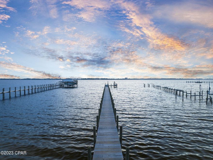 Nestled at the end of a private gated drive, this Panama City bayfront retreat offers a luxurious sanctuary with breathtaking views of St. Andrews Bay and stunning sunsets. Surrounded by meticulously landscaped grounds and mature live oaks, the home exudes an air of secluded elegance. Inside, more than 3,000 square feet of living space unfolds in a harmonious blend of comfort and luxury. The residence features four bedrooms, including two master suites — one on each floor. A separate carriage house provides two more bedrooms and 1.5 baths, bringing the total living space to six bedrooms and six baths. The heart of the home is a chef-inspired kitchen, perfectly designed for both culinary adventures and social gatherings. A hidden butler's pantry, complete with a dishwasher, sink and laundry chute, adds a layer of convenience and functionality. Stepping outside, the property transforms into an outdoor oasis. A state-of-the-art heated pool, complete with fountains, upgraded water jets and a lighting system, is surrounded by no-maintenance turf. For boating enthusiasts, a private dock with a boat slip offers direct access to the bay, just minutes from the pass and Shell Island. The home is also equipped with property-wide high-speed internet and Sonos media systems, making it an entertainer's dream. Adding to its appeal is its prime location, a short walk from the St. Andrews Historic District, offering easy access to local amenities and attractions. A two-car carport and full RV 50 amp hookup with cleanout complete the extensive list of features. In turnkey condition, this home is ideal for those seeking a hassle-free transition to their new waterfront paradise. Truly, this is a residence that must be seen to be believed.