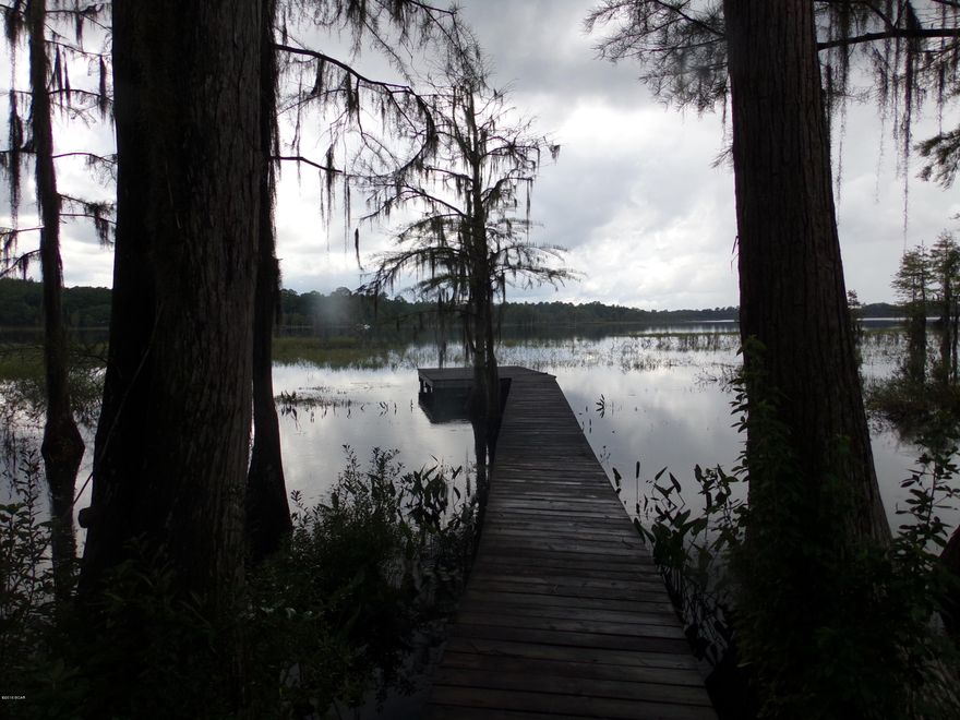 Beautiful lakefront lot on Lucas Lake with 90-feet on the lake.  This is a large crystal clear spring fed lake that always maintains its water level.  This lot is on a high bluff overlooking the lake.  The lot is semi cleared so it is easy to walk around on.  It is high and dry with no low areas and has an area on the bluff that would make a perfect homesite.  Beautiful native oak and magnolia trees.  This lot has a beautiful winding dock that goes out into the lake.  Catch brim, bass, and shellcracker right off your dock.  There is great hunting and fishing in all the area lakes and forests and is only 30-minutes to either Panama City or Chipley.  This property is on a paved road and is 1.8 miles out to State Hwy. 279.