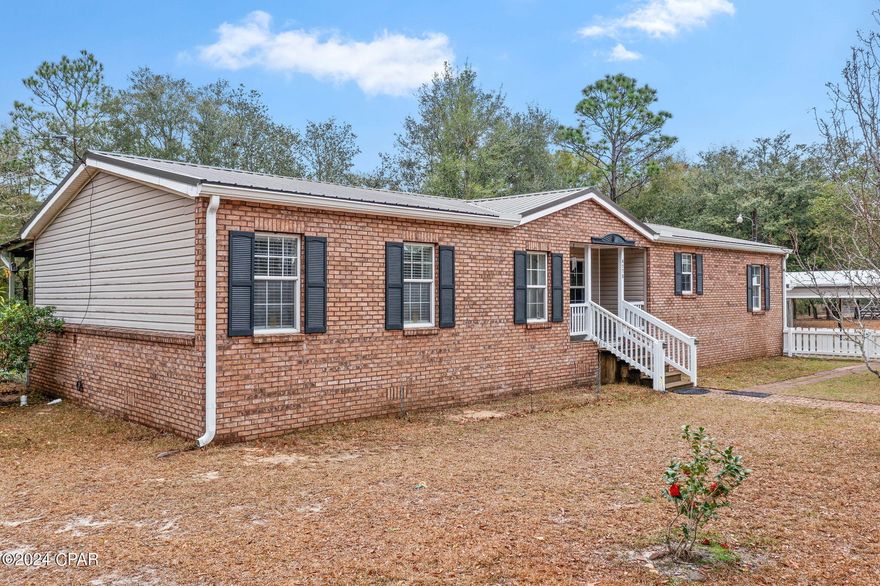 Welcome to country living at its finest! This charming mobile home with a brick front facade is situated on a sprawling 4.52+/- acres, offering space, comfort, and endless possibilities. With 3 bedrooms and 2 bathrooms, this residence is designed for both relaxation and functionality. Step inside to discover a spacious living room adorned with a wood-burning fireplace, creating a cozy ambiance for gatherings or quiet evenings at home. The adjacent formal dining room provides an elegant setting for hosting family dinners and in the kitchen you'll find an island with breakfast bar, perfect for casual meals and an abundance of cabinetry that ensures ample storage space for all your kitchen essentials. The split floor plan offers privacy and convenience, with the master bedroom situated away from the secondary bedrooms. Retreat to the master suite, complete with an en suite bath featuring double sinks, a jetted tub, separate shower, and a large walk-in closet. Step outside to enjoy the serene beauty of the countryside from the covered front porch or back porch that extends the length of the home, providing plenty of space for outdoor seating and entertainment. A fenced backyard offers a safe and secure area for children and pets to play. Additional amenities include a detached carport with 12x20 shop and a 31x53 barn, offering ample storage space for equipment, tools, or recreational vehicles. Home is perfectly situated close to Hwy 77, approximately 28 miles to Panama City and 20 miles to Chipley.