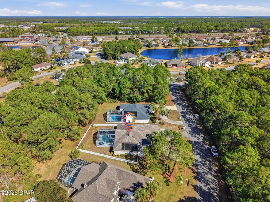 This beautifully renovated home offers a thoughtful split-bedroom floor plan with high-end finishes throughout. The renovated kitchen is designed for both everyday living and entertaining, featuring a gas stove, Sub-Zero refrigerator, abundant cabinetry, and generous countertop space. Wood floors run throughout the home, complemented by raised ceilings and custom lighting that enhance the open, airy feel.

A formal dining room provides the perfect space for hosting, while the large living room features custom built-ins and a unique palm-leaf twin-blade ceiling fan that adds character and charm. The primary suite is a true retreat, offering a spacious walk-in closet with custom shelving and a fully renovated bathroom complete with custom cabinetry, a deep soaking tub, and an oversized tiled walk-in shower.

A second primary bedroom includes exterior access leading directly to the pool area, ideal for guests or multi-generational living. The fourth bedroom features a convenient half bath, and all closets throughout the home are equipped with custom shelving systems.

Step outside to enjoy the screened-in in-ground pool with a covered patio, creating a private outdoor living space perfect for relaxing or entertaining. The home backs up to a wooded area, with additional wooded views across the street, offering privacy and a peaceful setting.

Centrally located in Panama City Beach, this home is just minutes from shopping, dining, and entertainment, a short drive to the beach, and approximately 10 minutes to Gulf Coast State College and Naval Support Activity Panama City, making it ideal for both full-time living and convenience-focused buyers.
