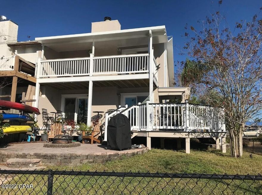 Beautiful canal-front townhome with porches and paver paths that will make you want to be outdoors. End unit home has canal on two sides and has been completely updated. Exquisite professional landscaping includes outdoor grill and fire pit. Hardi board siding, metal roof, pavers, a terrific playhouse for the kids, dock, and fenced yard are high-end extras. Kitchen upgrades include replaced cabinets, stainless steel appliances and glass mosaic backsplash