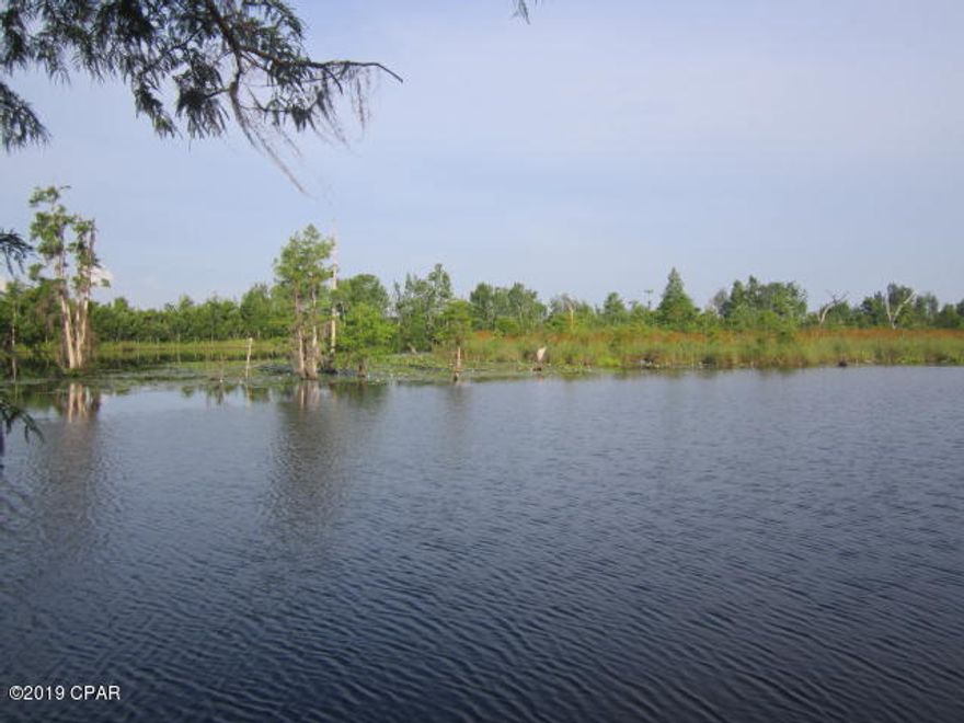 RARE WATERFRONT FIND ON DEER POINT LAKE. 3 LAKE FRONT LOTS WITH PLENTY OF POSSIBILITIES !!! 1.361 Acres with 200+ Feet of water frontage.  Well kept 31 ft 5th wheel on the land for a ''perfect'' weekend retreat or a place to live while building a home on stilts next to the water's edge! There is a small sitting porch added onto the 5th wheel Trailer. Two Electric power poles are on this FENCED lot plus a large work shop & a smaller storage building. There is a small dock + a place to park a boat next to the sea wall,  with a ramp entrance area to put in a boat. .... Easy access to fishing!   3 lots.....live on one and sell 2 of them.  This also could be the perfect place for a contractor to live and stage equipment while working in Panama City.  Wonderful Investment OpportunitY !!