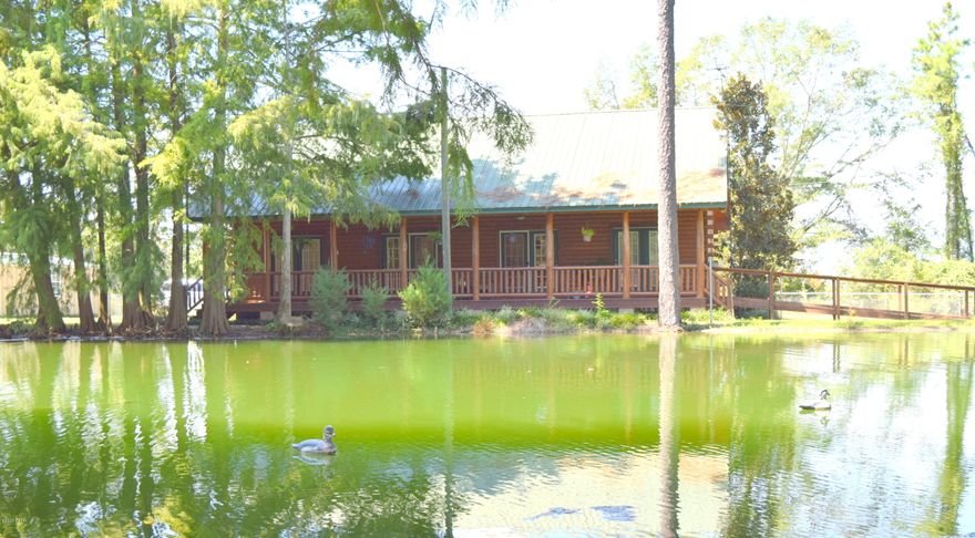Ever dreamed of owning a log cabin on the water? Well here is your chance! This 2-bedroom, 2 bath home overlooks a ½ acre stocked pond and boast an open concept layout, tongue and groove cathedral ceiling, spacious kitchen with island and 2 master suites with large walk-in closets and double sinks. Enjoy your morning coffee from the back porch watching the ducks, fishing from the dock, working inside the 32x16 steel building, frying fish in the cook shed or have company stay over at the detached mother-in-law apartment.  Other outside features include newly installed chain link fencing, detached 2 car garage, 3 wells (2'', 4'' and 8''), 2 septic tanks and an abundance of cypress trees providing shade and privacy.  Home is located close to the Chattahoochee River boat ramp and a short drive the Chattahoochee River boat ramp and a short drive to Marianna and Dothan.