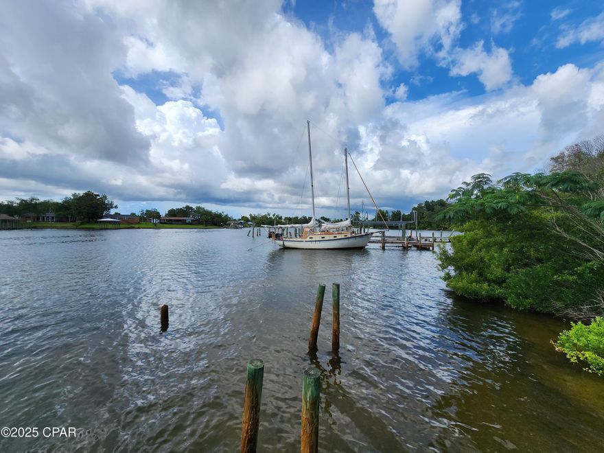 Rare diamond in the rough!  Zoned MU-1.  94.9 feet of shoreline on Pitts Bayou with deep water access to the Gulf.  Situated on .946 acres, the property features a single family home with over 2000 sq ft, 4 bedrooms and 2 bathrooms.  The kitchen and bathroom were updated within the last several years. Large inside laundry area with small office. Attached is a single car garage along with a carport and storage shed. New roof installed 2019. Gas stove and dryer convey.  There is a 20x40 workshop built with 2x6's instead of the standard 2x4's in the walls. Numerous shelving units are included for organization.  The large pole barn includes a power pole.   A deep well is located in the well house and was used for landscaping/gardening.  The well is currently nonfunctional as it needs a new water tank.  The City of Parker provides water to the property.   A single wide mobile home and a detached building (formerly a pawn shop) provide no contributory value as both are damaged and dated.  Numerous trees (pear, satsuma, loquats, pecan & hickory nut) are thriving on the property.  Located just across the DuPont Bridge from Tyndall Air Force Base, the surrounding area is expected to boom in the next few years with the completion of the construction and added squadrons to the base.  Property is being sold As Is.  Active security system in use.