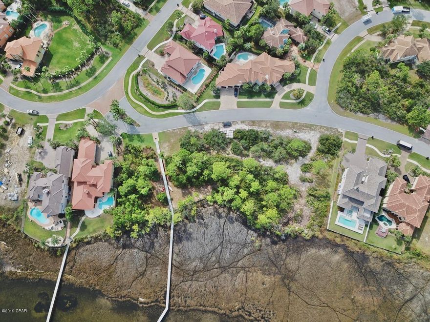 Lowest priced waterfront lot in the prestigious gated Mediterranean style architectural enclave of Finisterre. Build your custom home with views of St Andrews Park & Shell Island and watch sailboats on their journey through the Gulf Pass to catch a sunset. Amenities in Finisterre feature a dock, tennis court, half-court basketball and playground. This private, small neighborhood is on the east end of Panama City Beach, walking distance to Lighthouse Marina, Grand Marlin and Captain Anderson's.
