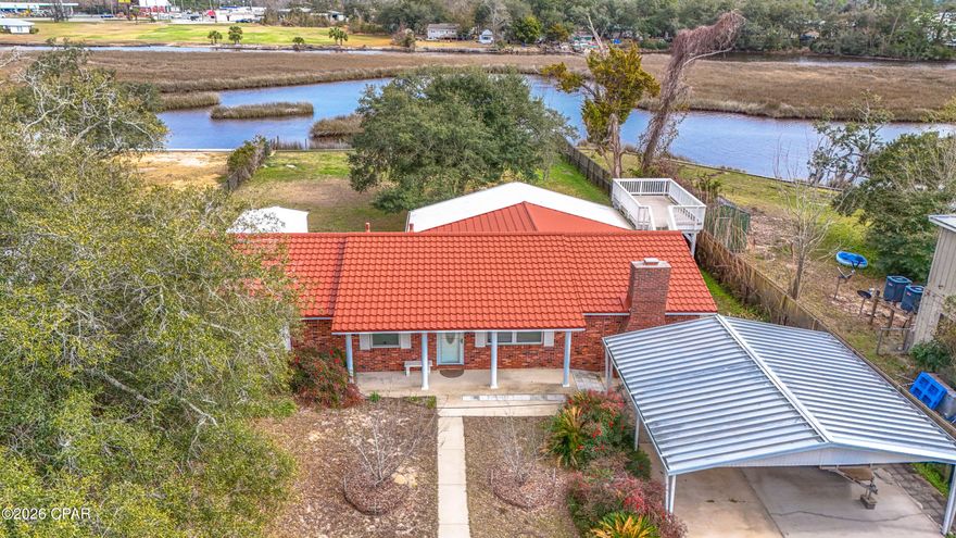 Experience waterfront living on deep-water Gulf access! Located on a canal, leading directly to the Gulf of America! This brick home offers easy access for boating, fishing, and kayaking along with wide water views and a private floating dock. A seawall, fenced yard, and a covered carport add everyday convenience. Inside, the large living and dining area features a carved marble fireplace and full height marble accent wall. Wood look porcelain tile flooring runs through the main living spaces, paired with matching baseboards for a clean, cohesive finish. Decorative tile ceilings and maple kitchen cabinetry bring additional character, highlighted by solid-surface countertops, built in microwave, and stainless-steel refrigerator. Both bathrooms include ceramic tile showers with glass doors and a tankless water heater adds efficiency. The screened back porch offers floor to ceiling views of the yard and water, while an elevated deck provides an additional outdoor space to take in the scenery. Almost half an acre lot is shaded by mature oak trees and features fruit trees, including figs, peaches, and mulberries. Major improvements provide peace of mind, including a 220-mph rated tile metal roof installed December 2024, new decking, underground electricity, and a new drain field for the concrete septic system. With direct Gulf access and a quiet natural setting, this property offers a practical, waterfront lifestyle with room to relax and enjoy coastal living. Only around ten minutes to stores and restaurants. Please verify all measurements and information.