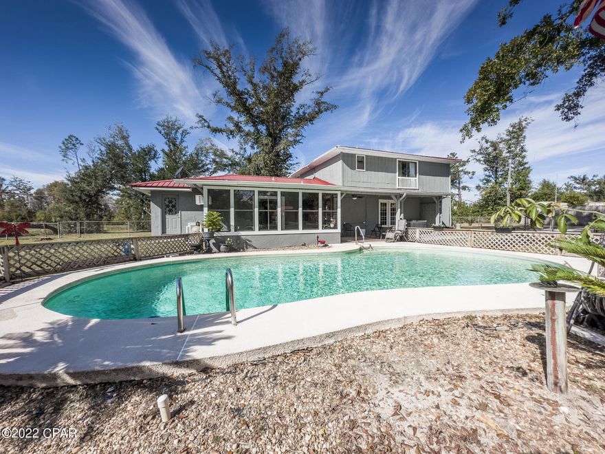 CURRENTLY UNDER CONTRACT, SELLER WILL CONSIDER BACKUP OFFERS Peaceful comfortable living on beautiful and sprawling 2.5 acre lot with fruit trees (orange, peach, tangerine), oaks, pond, and a small winding stream. Enjoy the sun or shade with open, covered, and enclosed patios or take a swim in the inground pool!

This well built home offers low maintenance living with updated air conditioning, water heater, metal roof, and fresh exterior paint. Featuring an extra large kitchen with island and breakfast bar, spacious dining room, and a living room designed for entertaining. The living room contains a wet bar, fireplace, and guest bath with an additional bedroom, and bonus room or office. The 2nd floor contains the master suite, two additional guest rooms, and guest bathroom. Detached 1 bed 1 bath guest home has a large open living space with kitchen, new spray foam insulation, new roof, fresh paint, and more. Perfect for your small business, entertaining, guests, rental unit, or hobbies! The 18' x 24' pole barn is on concrete slab and has power. 

Only a block to Simmon's Park with playground, 5 Miles to Lynn Haven, and only 5 Miles to Public boat ramps with access to Deerpoint Lake (freshwater), and North Bay (Gulf Access!). Near top rated schools, numerous large parks, equestrian areas, outdoor recreation, and an international airport.