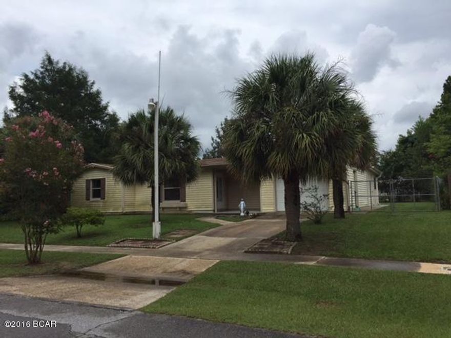 Vinyl sided home in Sunny Hills with 898 sq ft heated and cooled, and 1626 sq ft under roof. Home has a garage facing the street, several palm trees, sidewalks, and a storage building in backyard. House has 2BR/1BA and 2 rooms added on back for extra space.