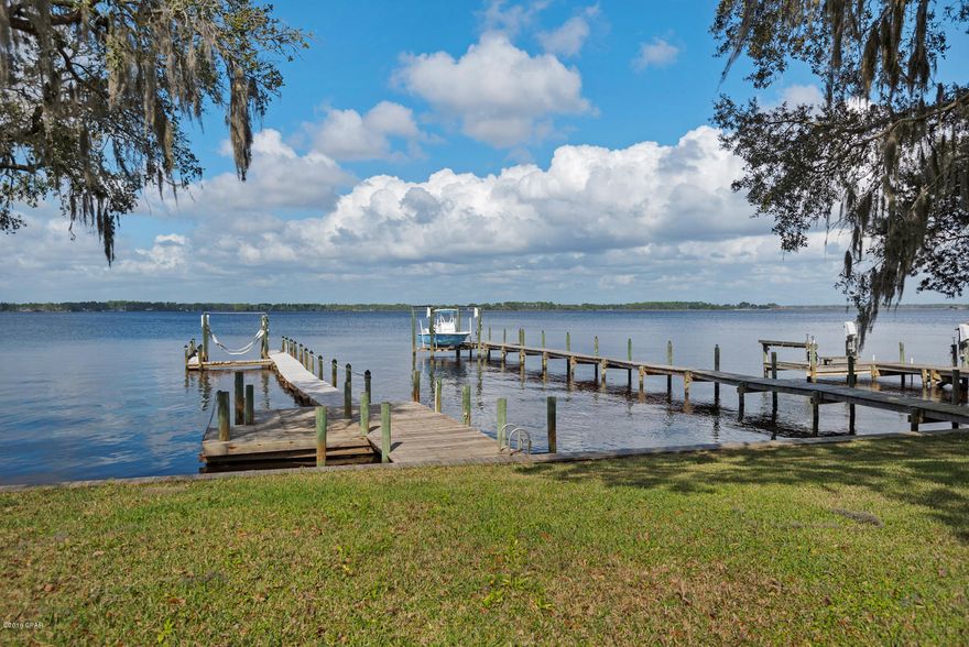 Beautiful waterfront townhome with a boat dock/slip and 10,000 pound boat lift in the Panama Country Club in Lynn Haven. Open floor plan, w/vaulted ceilings, a wet bar and two master bedrooms/bathrooms and masterfully updated tile showers. SPACIOUS loft master suite upstairs. Gorgeous kitchen with custom cabinetry, granite countertops, an exquisite back splash, and stainless appliances. Covered deck on the bottom floor and walk around loft and balcony upstairs for breathtaking views of North Bay. Seawall replaced in 2012 and new roof in 2016. Peaceful, waterfront living in the heart of this historic and inviting golf course community. **FULL VIDEO under Photos tab.