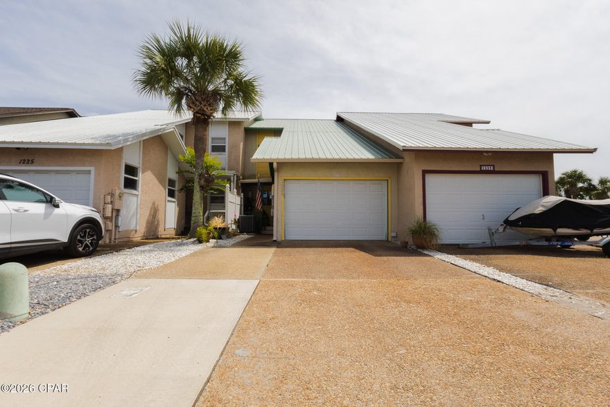 Waterfront townhouse with canal views and bay access at 1227 Capri Dr, Lynn Haven, FL. Bring your boat, kayak, or paddleboard and enjoy the peaceful coastal lifestyle with stunning sunset views. Located in Venetian Villa, this beautiful canal-front townhome offers unobstructed waterfront views and a well-designed open floor plan.

The first floor features ceramic tile, a spacious living and dining area, and an inviting kitchen equipped with a modern touchless faucet for added convenience. A stone fireplace creates a cozy atmosphere for cooler months. Step outside to the downstairs deck, perfect for relaxing or enjoying direct canal access for a small boat or jet ski. The decks were redone in 2022 with Trex Enhance decking for low maintenance and include an electric Sunsetter awning, creating a comfortable shaded outdoor space.

Upstairs you'll find 3 bedrooms and 2 baths, all carpeted, with large closets and plenty of storage space. The primary bedroom features a private balcony with ceiling fans, and a hammock that conveys with the home, making it a fun and relaxing spot to unwind and enjoy the sunshine and water views. After a fun day on the water, relax in the double jacuzzi tub.

The first floor also includes a half bath, laundry area, and access to the attached one-car garage. Centrally located in Bay County, this well-kept waterfront property offers the perfect blend of comfort, convenience, and coastal charm.