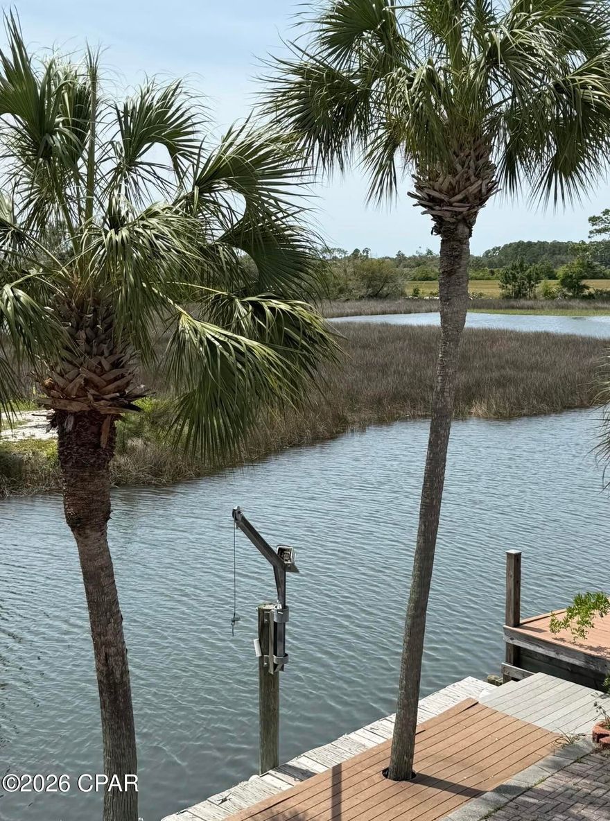 Waterfront townhouse with canal views and bay access at 1227 Capri Dr, Lynn Haven, FL. Bring your boat, kayak, or paddleboard and enjoy the peaceful coastal lifestyle with stunning sunset views. Located in Venetian Villa, this beautiful canal-front townhome offers unobstructed waterfront views and a well-designed open floor plan.

The first floor features ceramic tile, a spacious living and dining area, and an inviting kitchen equipped with a modern touchless faucet for added convenience. A stone fireplace creates a cozy atmosphere for cooler months. Step outside to the downstairs deck, perfect for relaxing or enjoying direct canal access for a small boat or jet ski. The decks were redone in 2022 with Trex Enhance decking for low maintenance and include an electric Sunsetter awning, creating a comfortable shaded outdoor space.

Upstairs you'll find 3 bedrooms and 2 baths, all carpeted, with large closets and plenty of storage space. The primary bedroom features a private balcony with ceiling fans, and a hammock that conveys with the home, making it a fun and relaxing spot to unwind and enjoy the sunshine and water views. After a fun day on the water, relax in the double jacuzzi tub.

The first floor also includes a half bath, laundry area, and access to the attached one-car garage. Centrally located in Bay County, this well-kept waterfront property offers the perfect blend of comfort, convenience, and coastal charm.