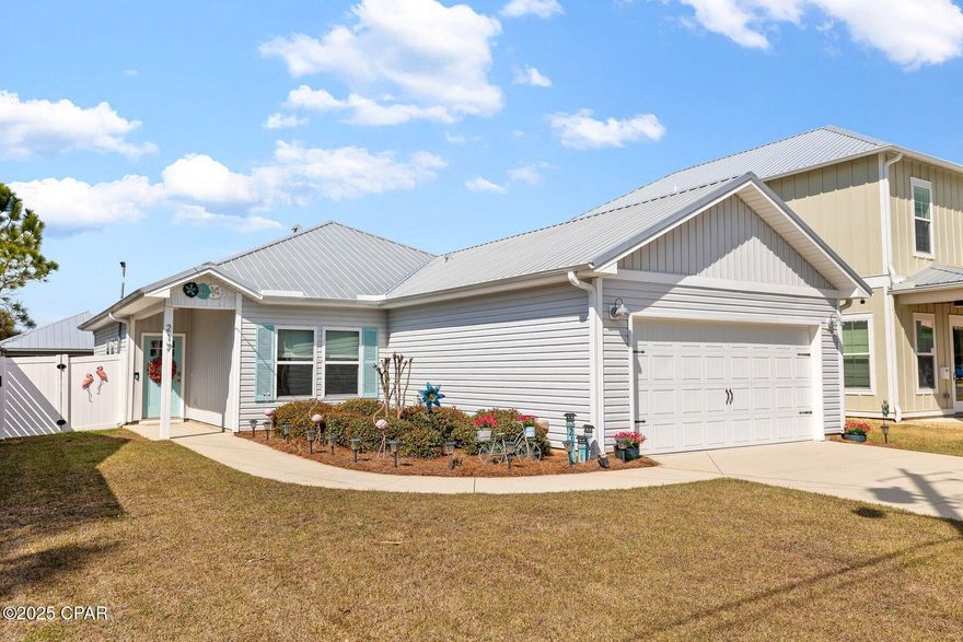Located at the quieter west end of Panama City Beach, this gently used beach house is fully furnished and ready to welcome part-time or full-time owners. Oozing traditional charm, this coastal gem has a broad driveway for parking and a two-car garage for storing bicycles and beach toys. After all, the beautiful white sandy beach is just a three-minute walk from the door. The covered side entrance opens into a hallway for you to pause before entering the open-concept living room, which has design and decor chosen by Susan Silverthorn Designs. Luxury plank flooring and a soaring tray ceiling provide a sense of abundant light and space. French doors offer additional natural light, opening directly onto the rear deck. The kitchen is larger than average and includes a handy breakfast bar for families to grab a bite to eat or socialize. Soft-close, white, Shaker-style cabinets and stainless steel appliances add a sense of luxury, along with the quartz countertops and glass tile backsplash. Move into the dining area for family meals or relax on the corner sofa and watch TV together after a busy day of shopping, swimming and shelling. Three bedrooms and two bathrooms allow everyone to spread out and enjoy their own private space. The master suite has a neat sliding barn door hiding the ensuite bathroom, which has a double vanity and a shower with floor-to-ceiling tile. Built in closets and drawers surround the wall-mounted TV, providing ample storage in the bedroom. Two additional bedrooms have larger closets. They share a modern family bathroom, which includes a tub and shower combo. A separate laundry room houses the washer and dryer. The enclosed rear yard provides a private space for kids and pets to play safely. Easy to maintain, it has a raised wooden deck for adults to relax and chill. This well-designed home includes energy-efficient LED lighting throughout, a WiFi-enabled garage door opener, a Smart thermostat and WiFi-enabled irrigation. This golf-cart-friendly neighborhood is just minutes from two large grocery stores, local golf courses and access to Scenic Highway 30A. Camp Helen State Park provides ample recreation nearby, and Rosemary Beach is well known for its boutique shopping and dining experiences.