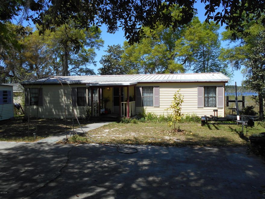 This waterfront lot on Deerpoint Lake is a fisherman's dream. This three bedroom two bath mobile home is located on over 1/2 acre, and offers some of the best freshwater fishing this area has to offer!! With an open floor plan, this home has laminate flooring, a tiled master bath, a fireplace, and a newer AC system. There's a seawall in place, and a gazebo and fish cleaning area down on the water's edge. Lots of large trees, including magnolia, oaks, cypress, and fruit trees. You will also find electric gates, a large carport, 2 out buildings, an above ground pool, 2 vegetable gardens, and 10x34 partially covered deck overlooking the water. Owner financing is available with acceptable offer. Call for details. Being sold partially furnished, and AS IS. Measurements approx.