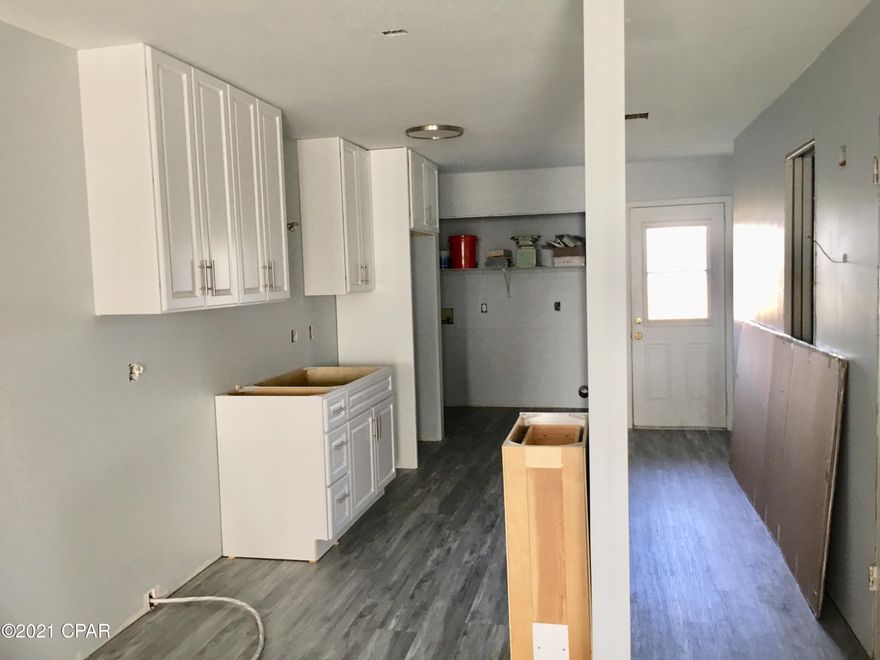 Out of state owner has gotten a great start bringing this unit up to date with modern finishes. With new VINYL PLANK FLOORING, interior paint in SHADES of CALM, and a back yard partially PRIVACY-FENCED overlooking a peaceful POND, the OPEN PLAN offers GENEROUS spaces. This home already has SOME NEW in place: 2019 ROOF, HVAC, WATER HEATER, Sheetrock, some kitchen cabinets with soft-close doors, tubs, lighting, and modern-style ceiling fans. Purchased BRAND NEW and ready for installation are additional kitchen cabinets and bathroom pieces. No HOA fees! Located in the GARDEN CLUB area near HISTORIC Beach Drive, St Andrew Bay, and Johnson Bayou, you're a short distance to both DOWNTOWN and a large MARINA with EXCITING PLANS for future expansion.