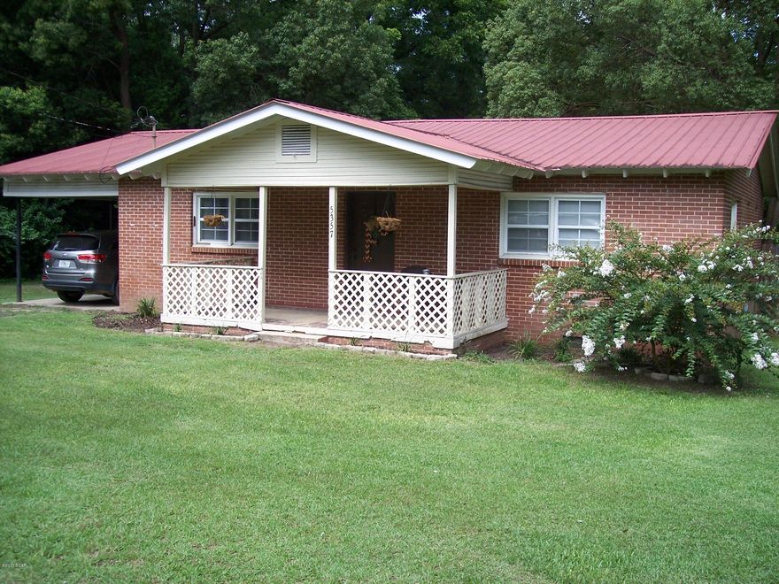 Brick home in town with pretty yard--porch on front and full length of house in back. Clean and well kept with updated floors, hot water heater, energy efficient windows, freshly painted walls and cabinets with new hardware.  All rooms are spacious and has an eat-in kitchen.  A single carport and a storage room that opens from the carport. Inside the home is a separate laundry room. Must see photos!